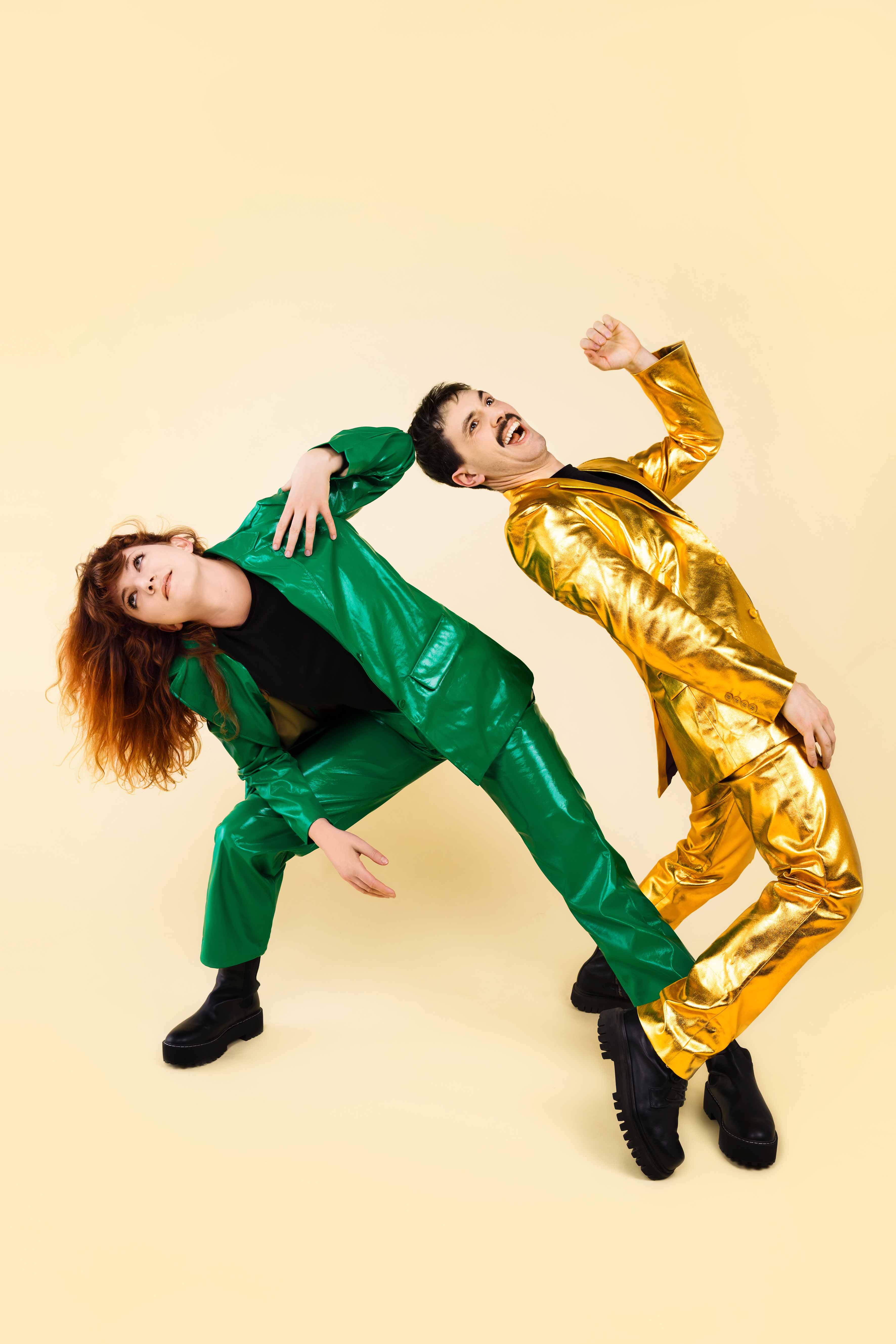Toukan Toukän, duo en costumes vert et doré, posant en déséquilibre sur fond crème