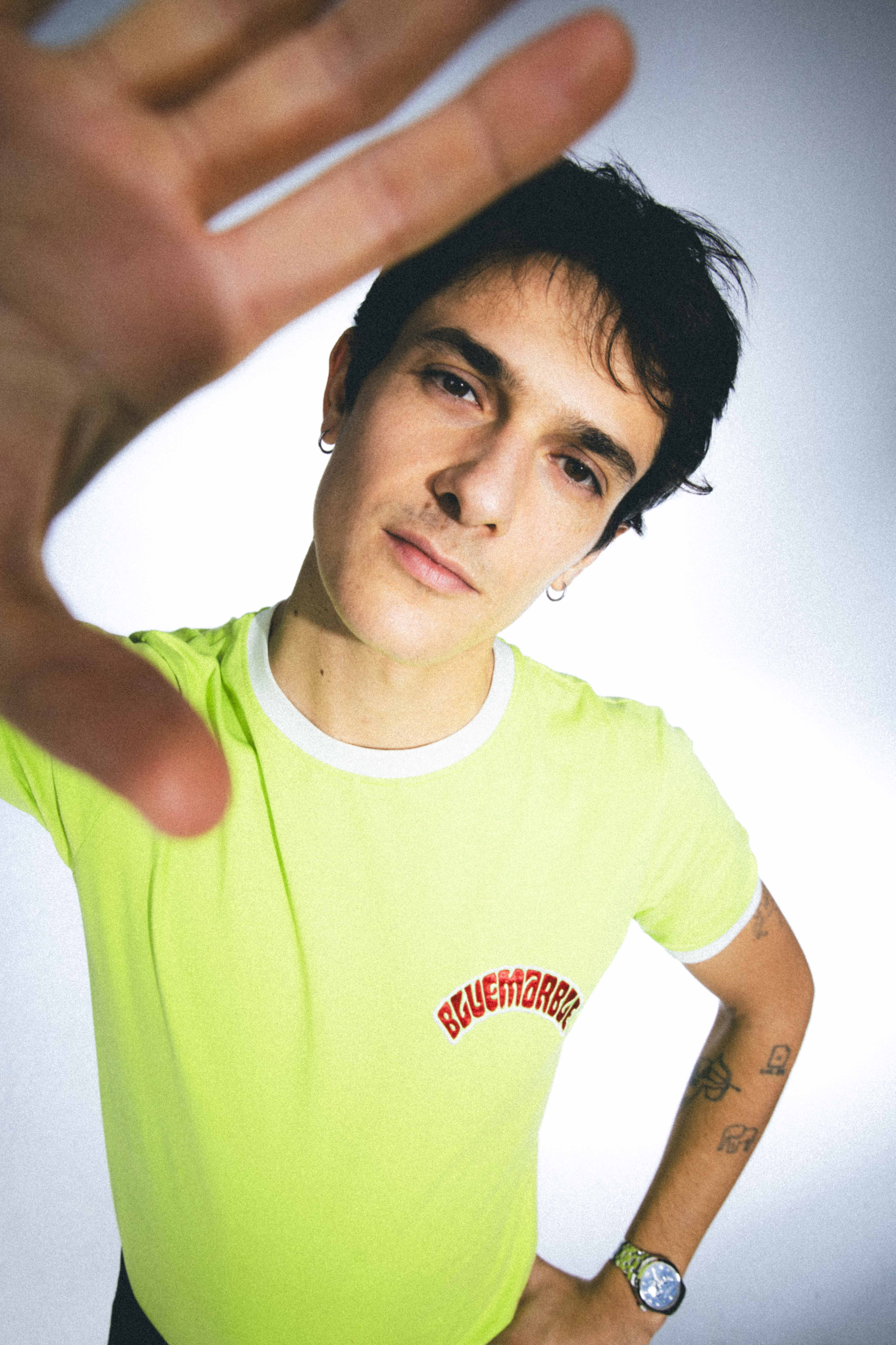 Portrait de Kungs en t-shirt vert fluo, la main tendue vers l'objectif