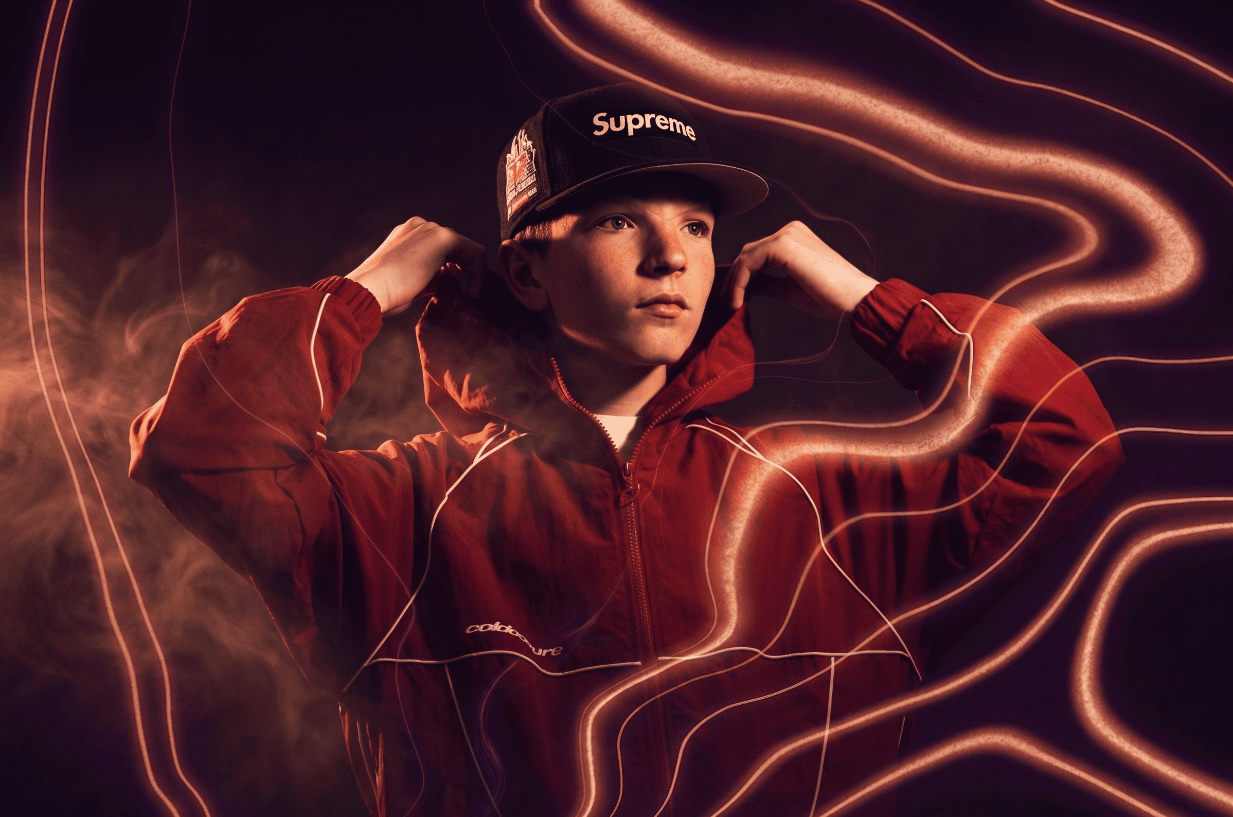 Elfigo, casquette Supreme et veste rouge, capuche relevée, entouré de traits lumineux orange