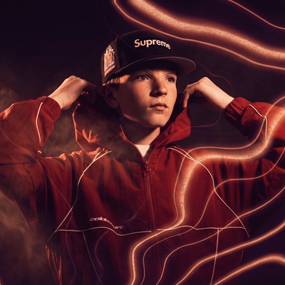 Elfigo, casquette Supreme et veste rouge, capuche relevée, entouré de traits lumineux orange