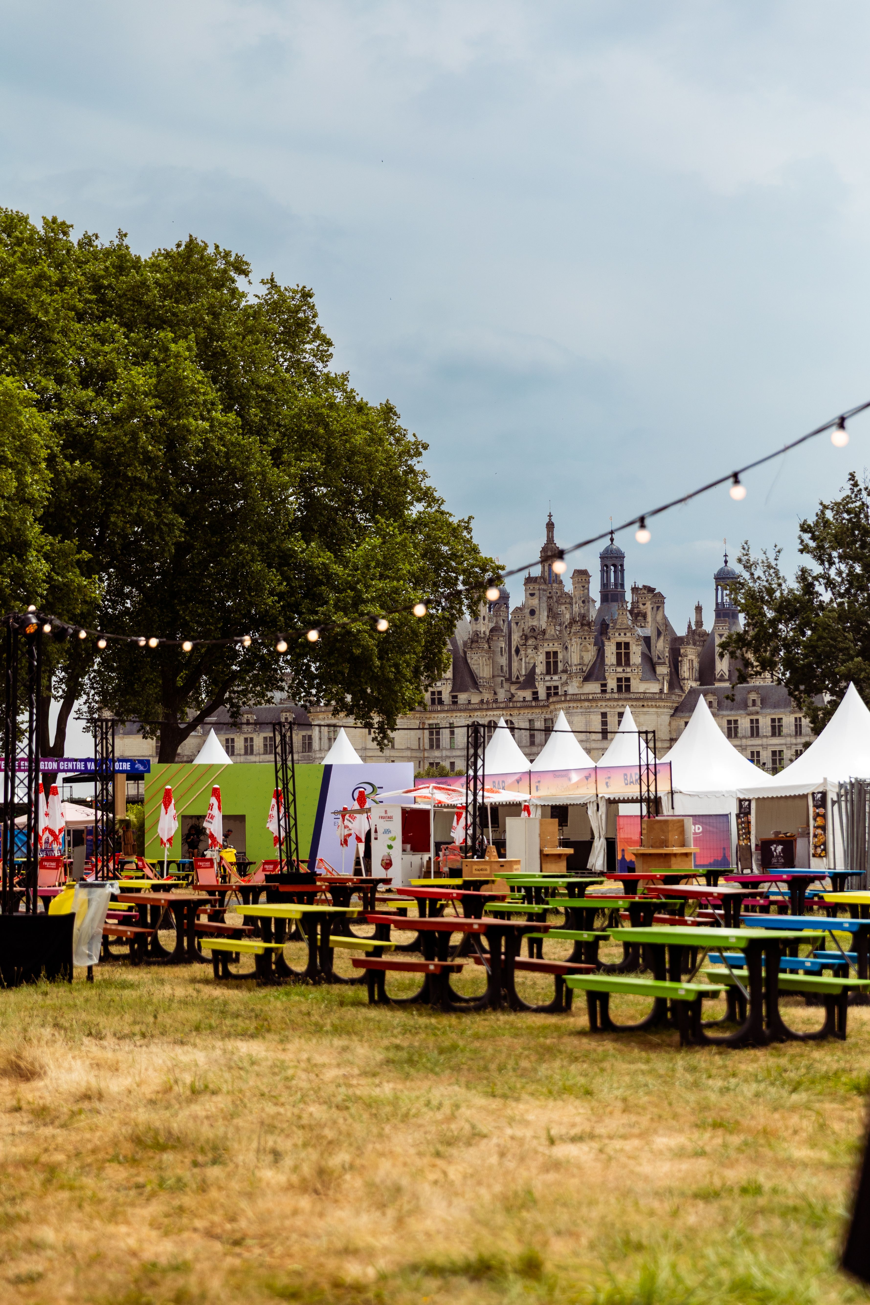 Le village du festival vide, tables colorées et tentes blanches devant le château de Chambord