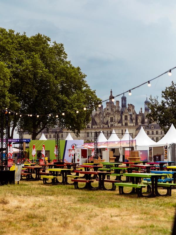 Le village du festival vide, tables colorées et tentes blanches devant le château de Chambord