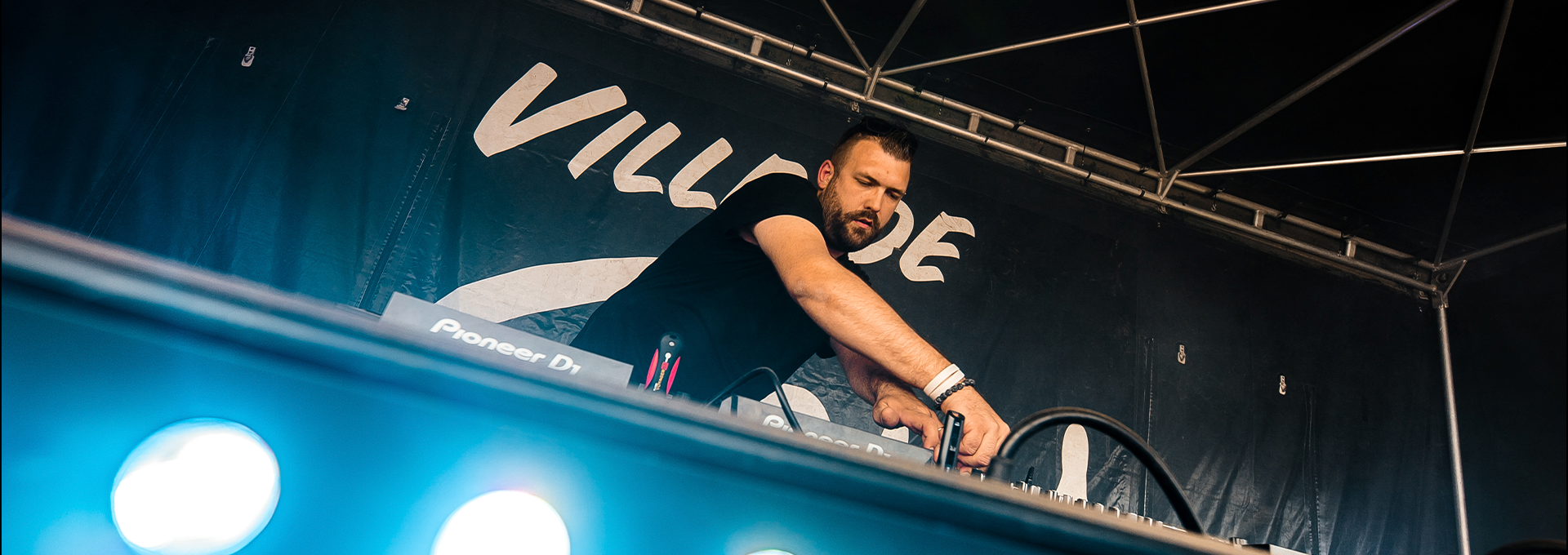 Da Julian aux platines sous une tente de scène, penché sur sa table de mixage