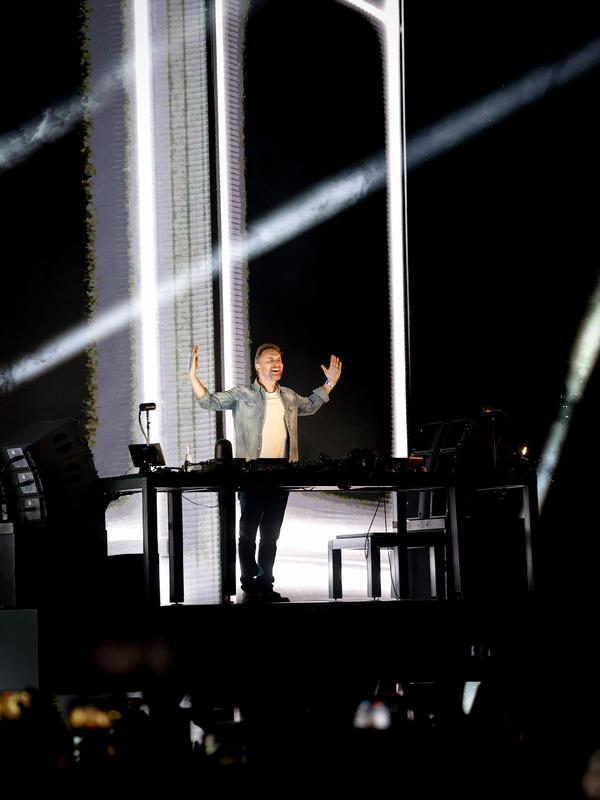 David Guetta bras écartés derrière ses platines, devant un écran blanc sur la scène de Chambord Live