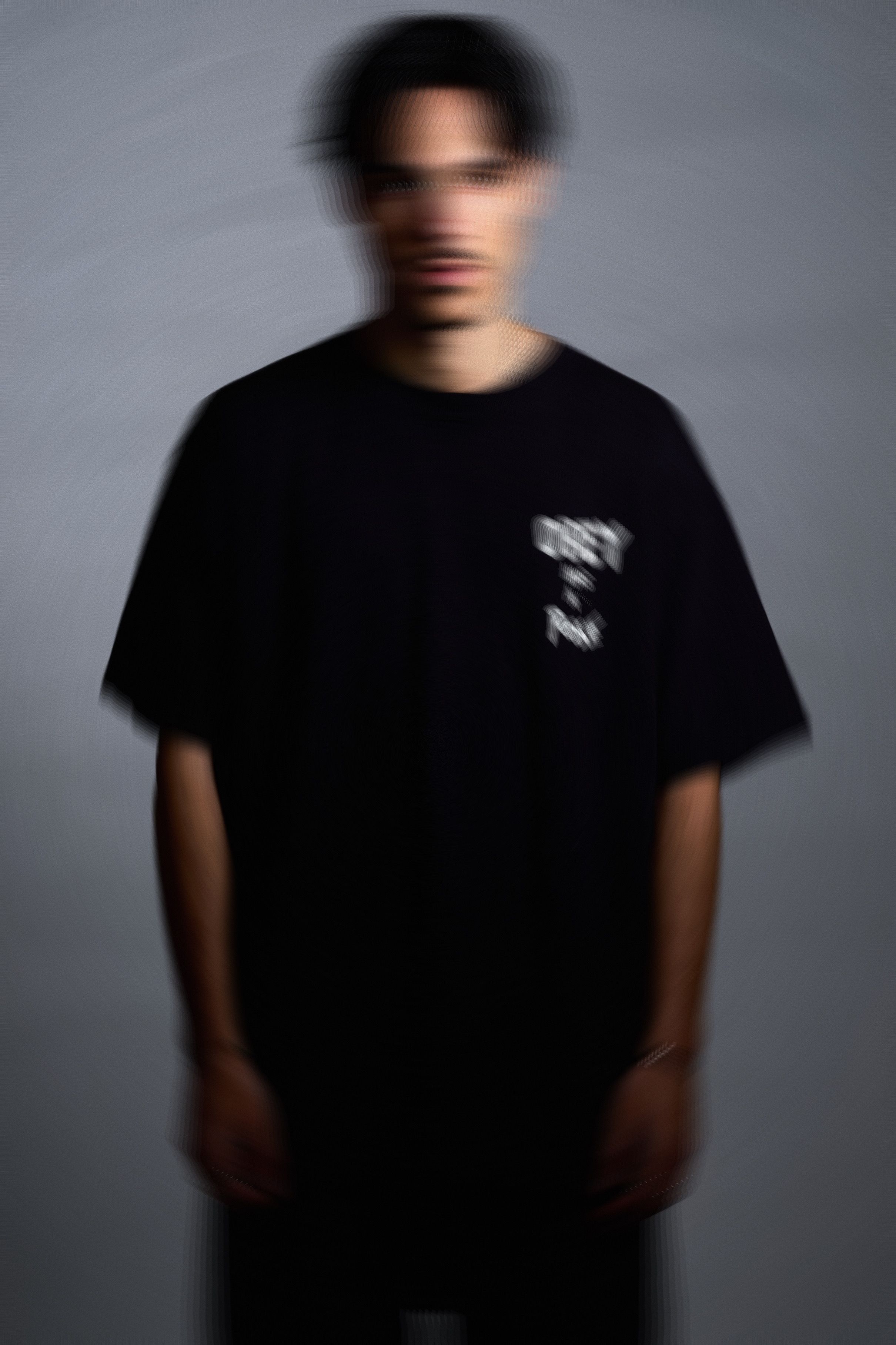 Portrait flou de Raffa Guido, debout en t-shirt noir sur fond gris