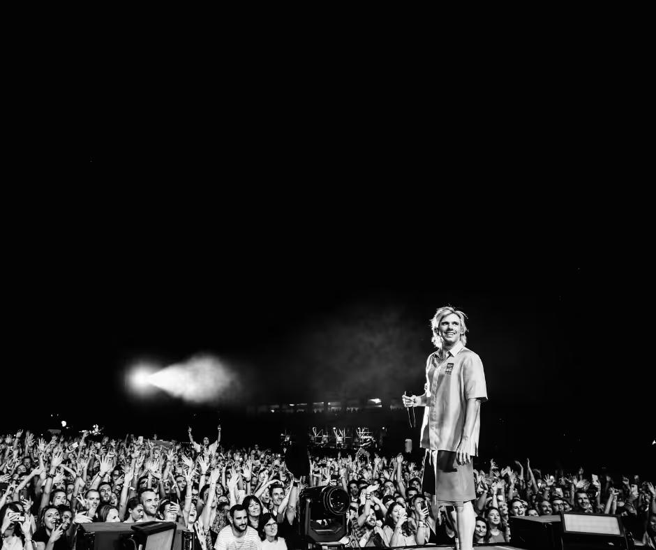 Orelsan debout sur scène face au public, photo en noir et blanc