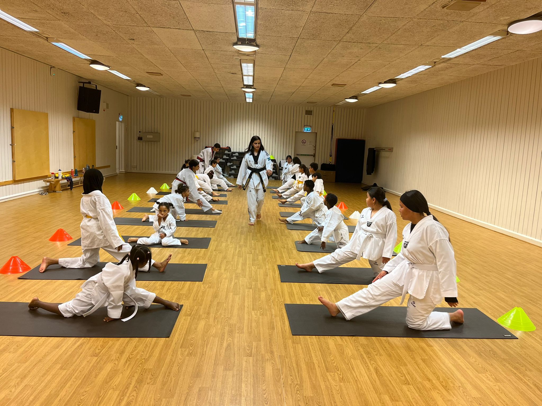 a group of children are doing stretching exercises on yoga mats in a gym .