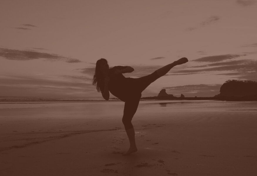 a woman is kicking her leg in the air on the beach .