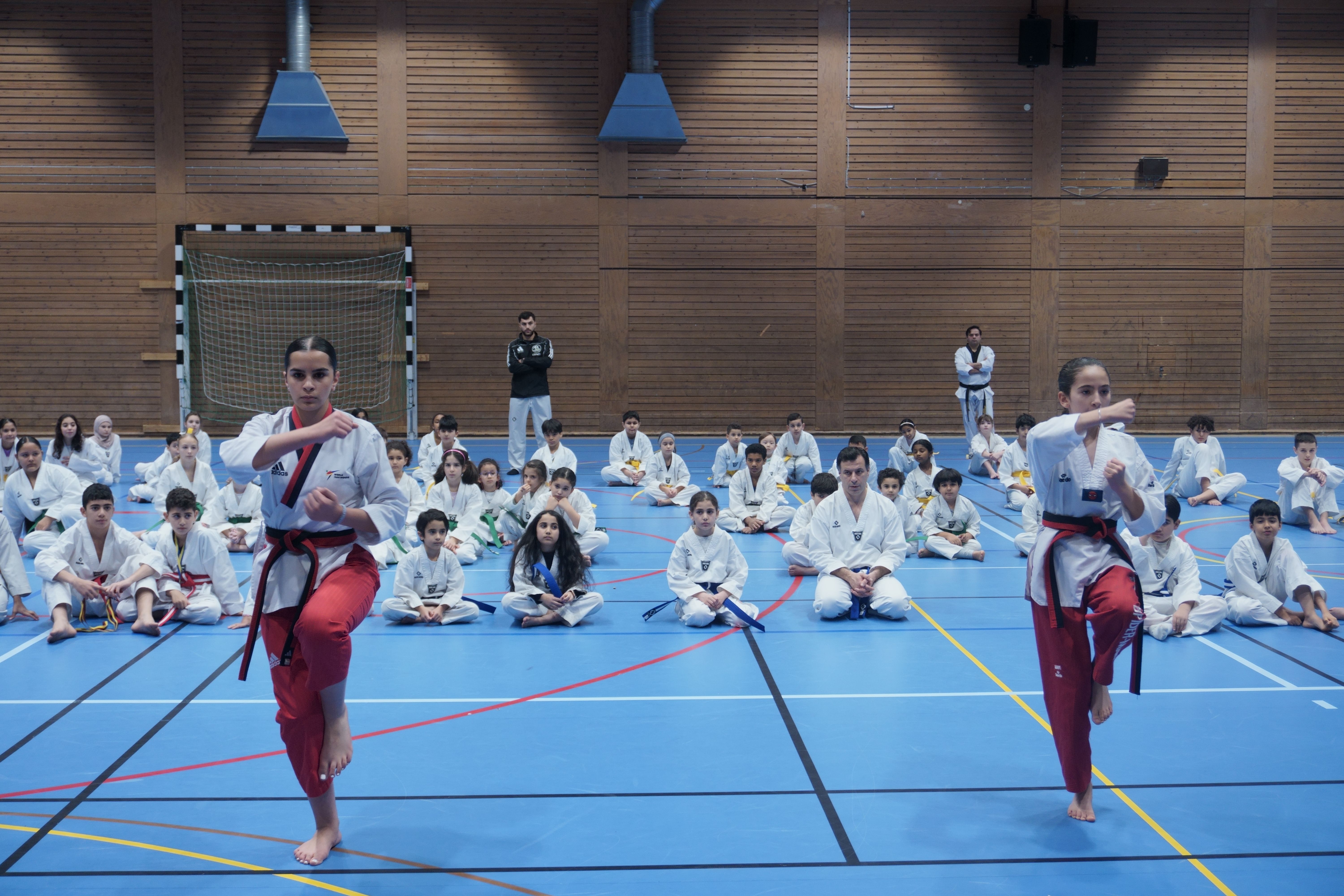 en grupp barn gör stretchövningar på yogamattor på ett gym.