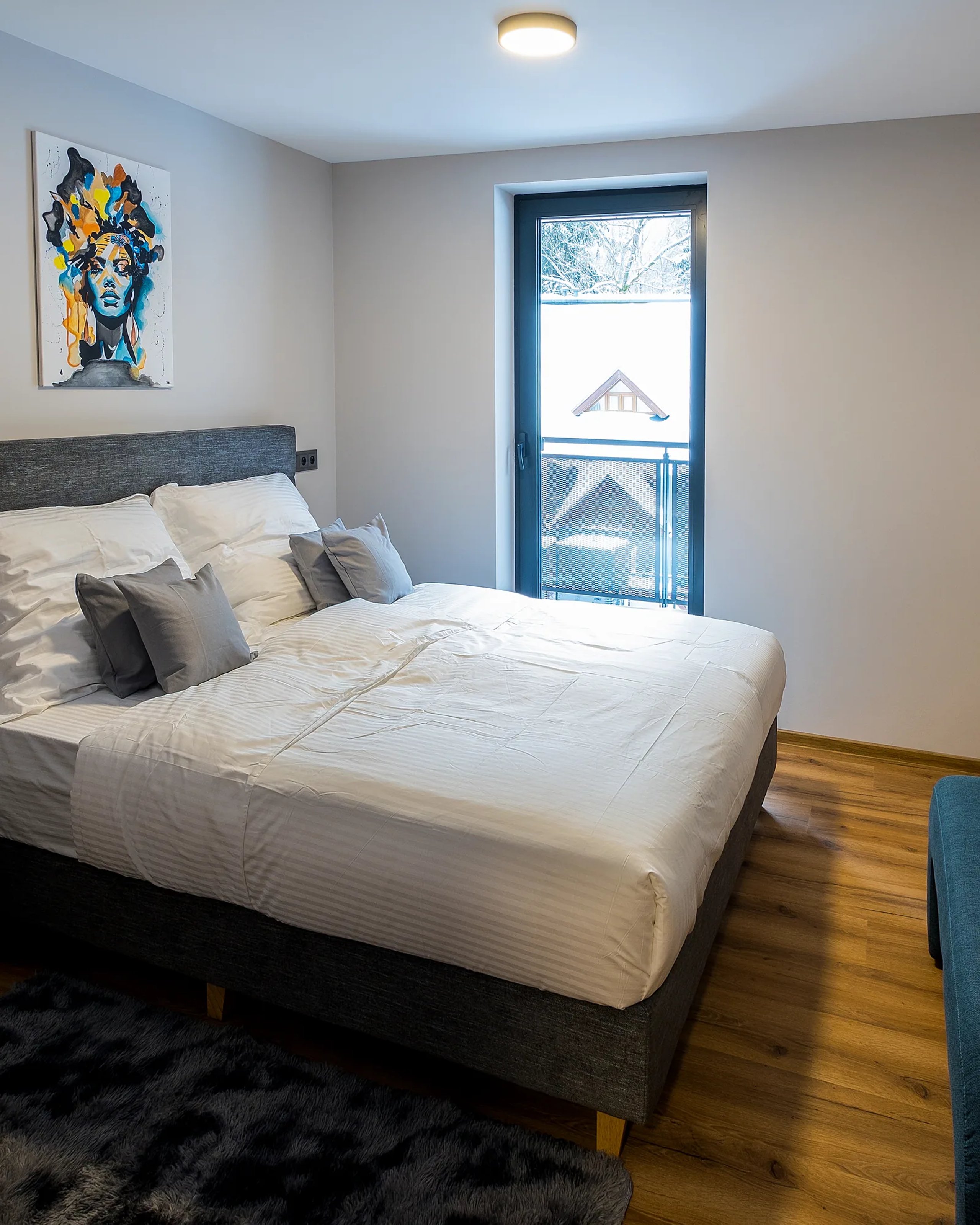 Bedroom of a Jarmilka apartment with a double bed and a teal bench