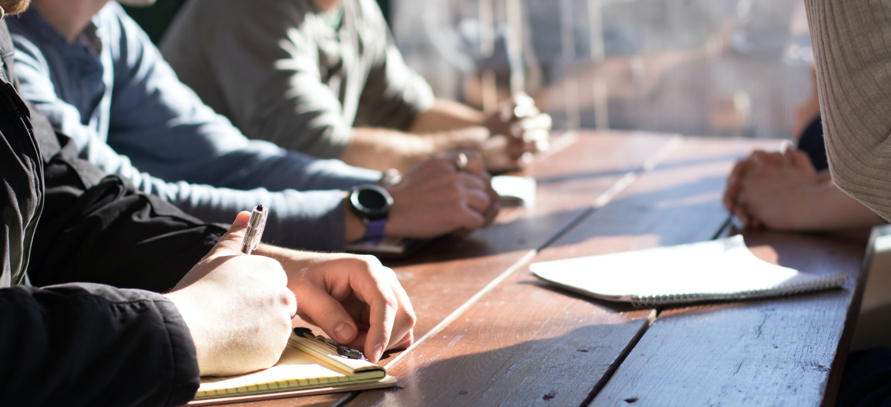 People sitting at meeting table with notepads in hand