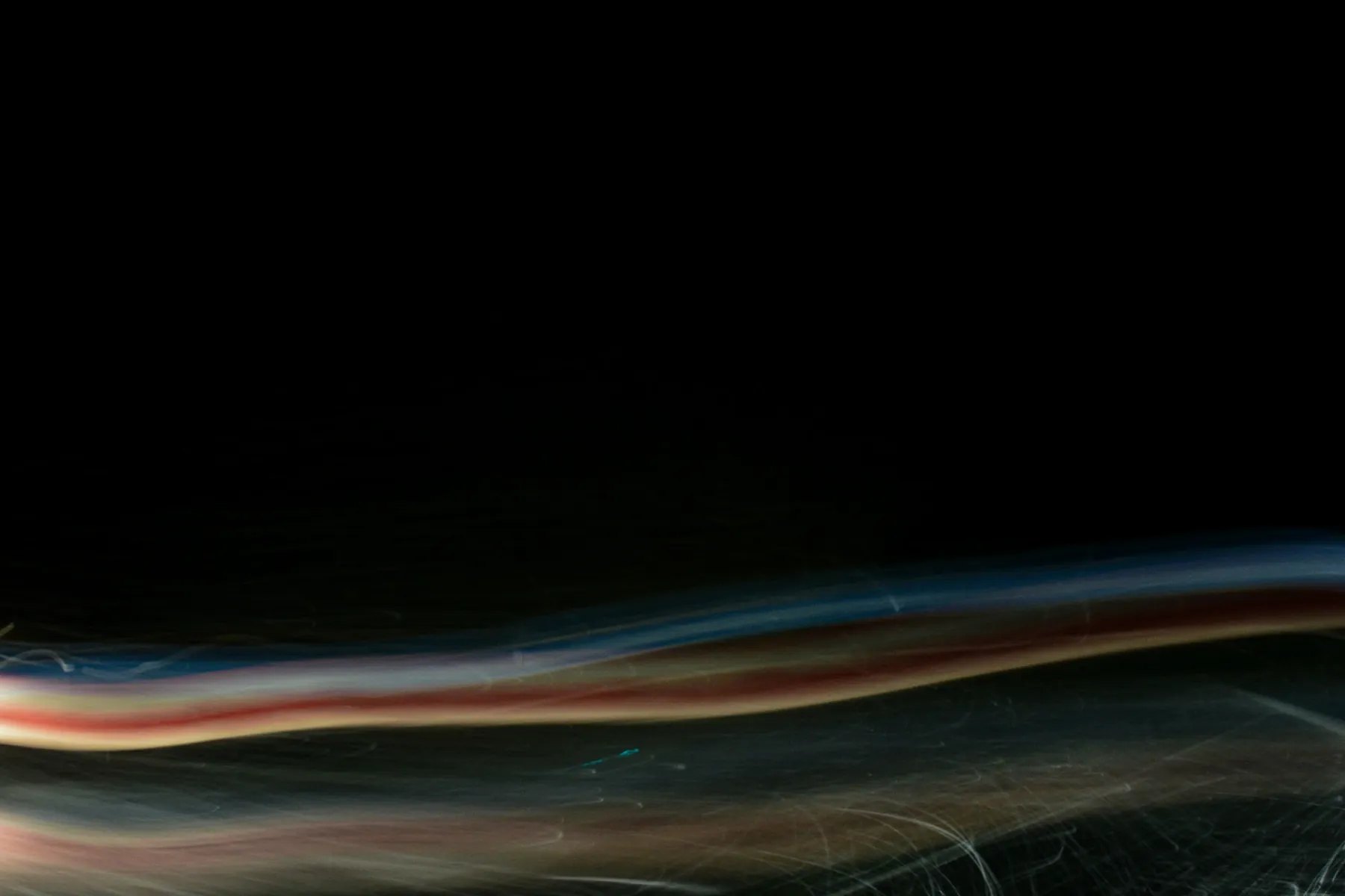 A restrained horizontal light trace crossing a black field
