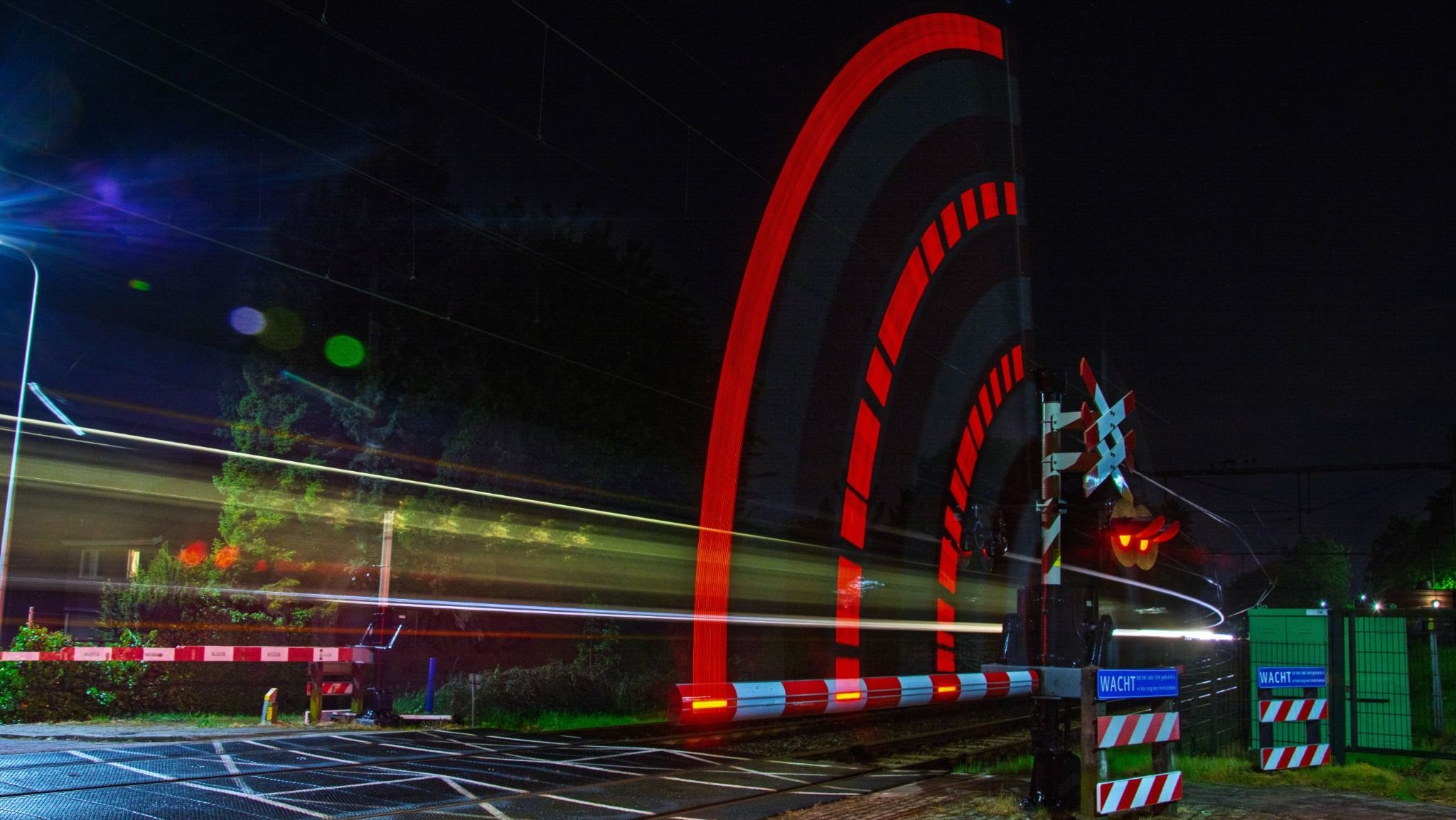 Red railway crossing light traced through a dark night crossing
