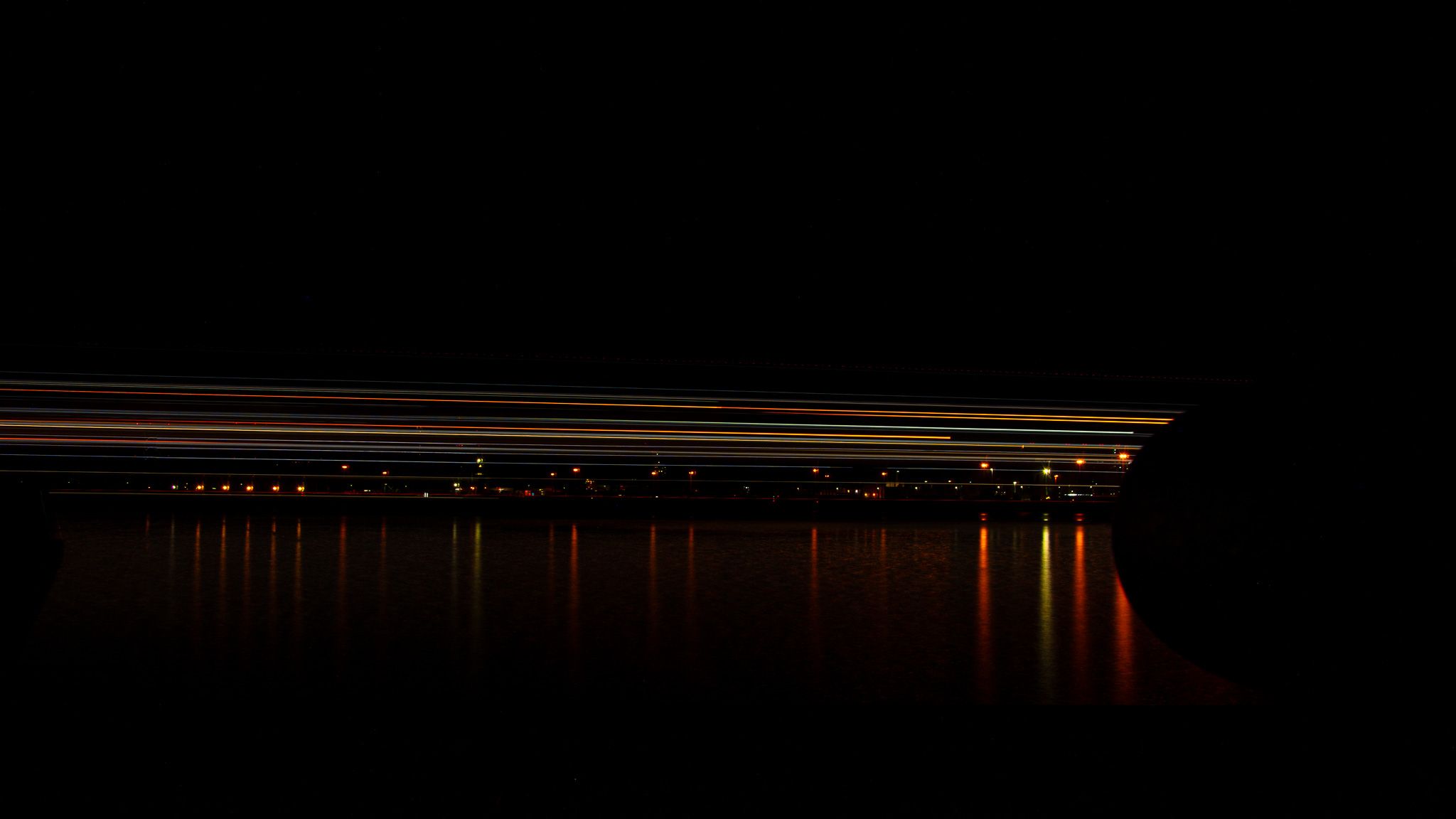 Long bands of ship light passing over black harbor water