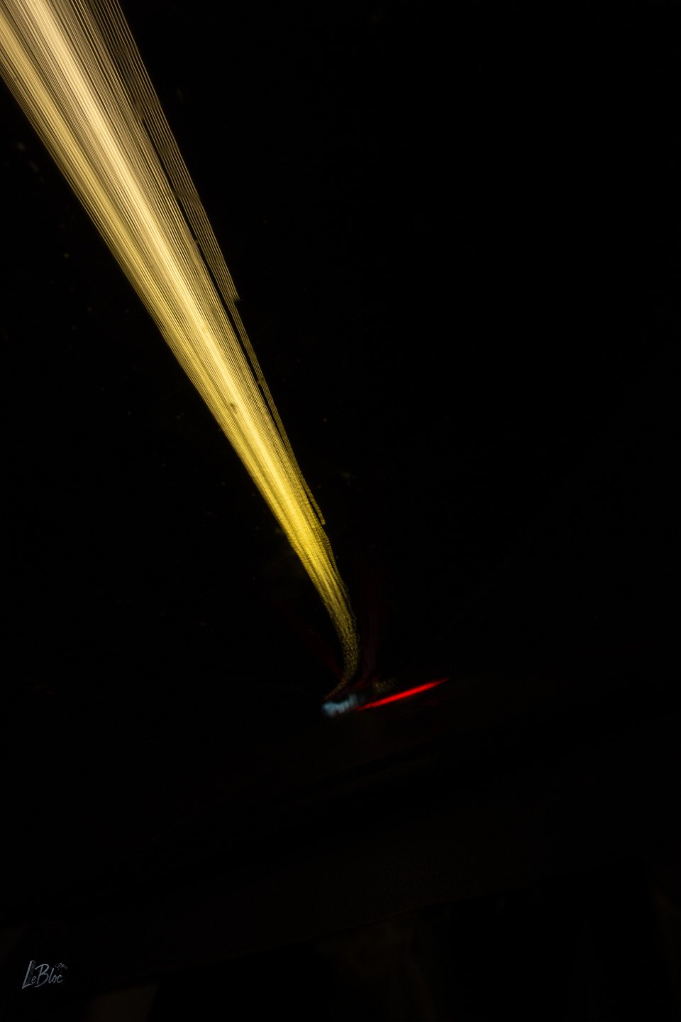 A denser golden stream of tunnel light compresses toward a red signal in black