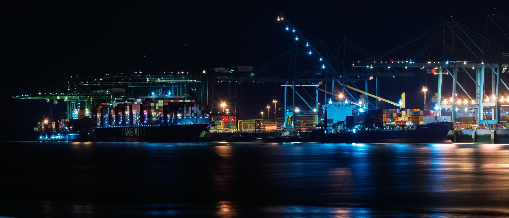 Container ships and cranes lit across the Kallo lock at night