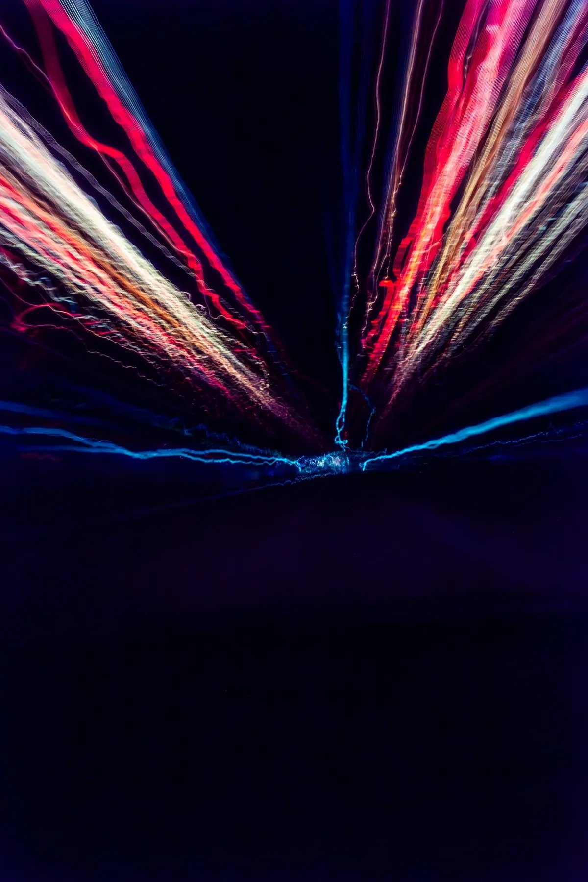 A vertical burst of red white and blue light opening into black