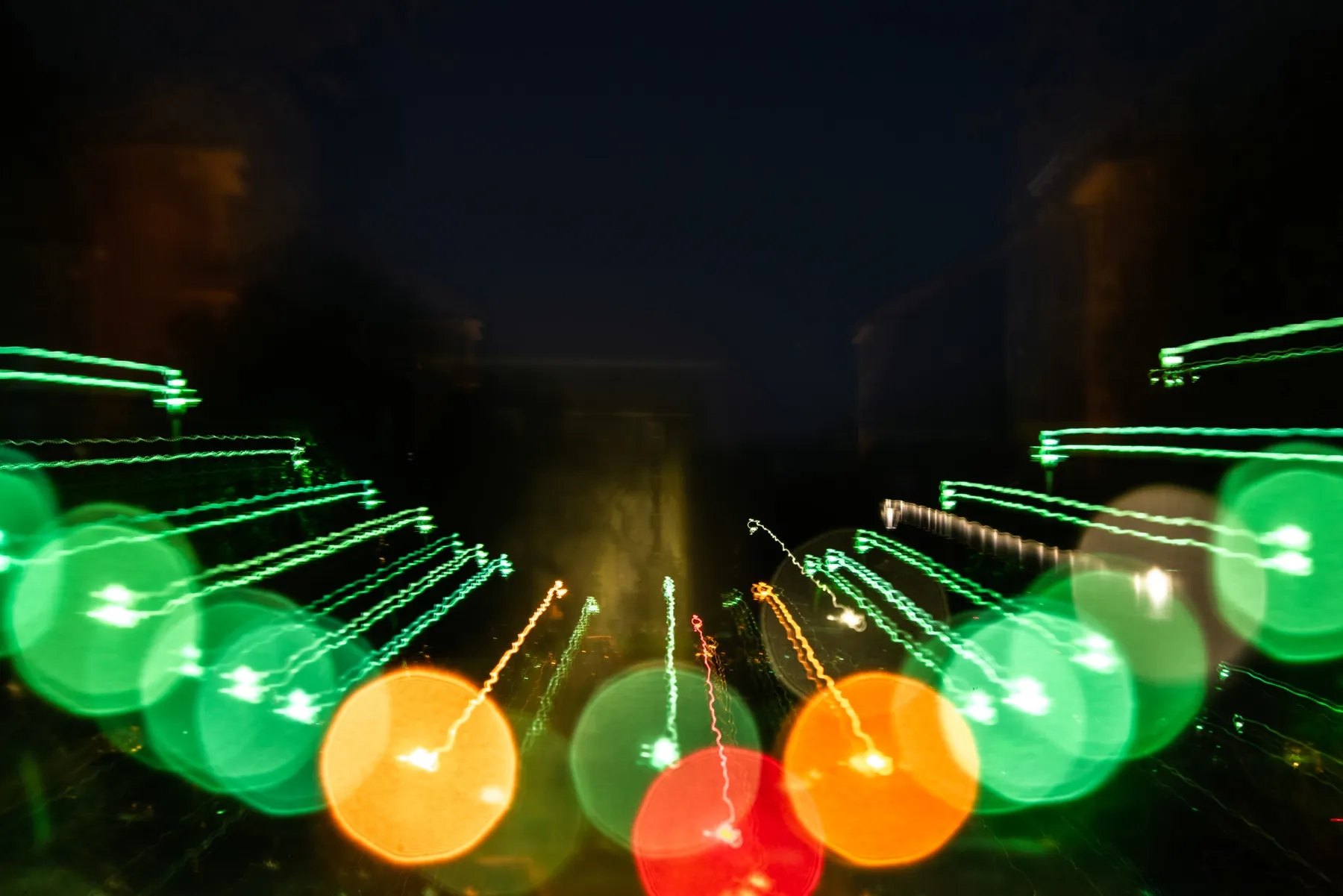 Green and amber light circles moving through a dark street field
