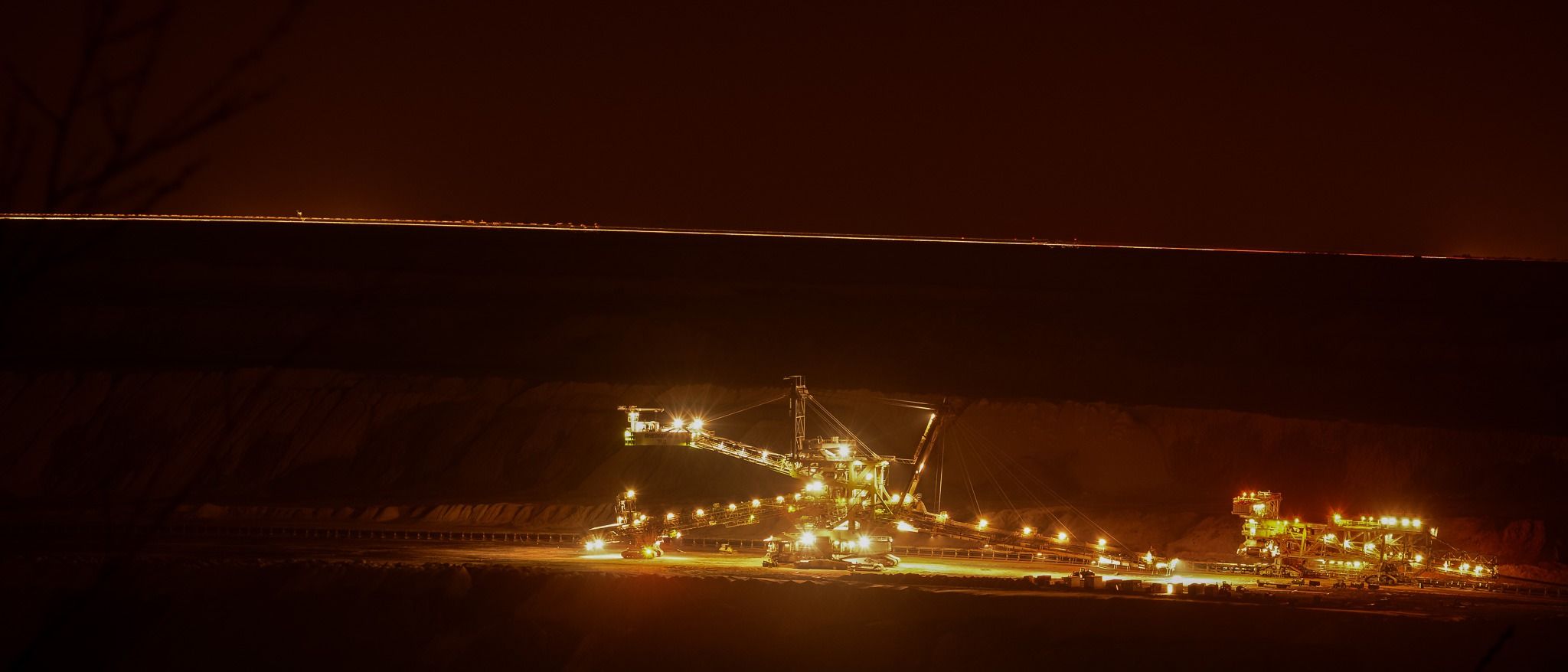 A vast illuminated mining machine cutting through darkness