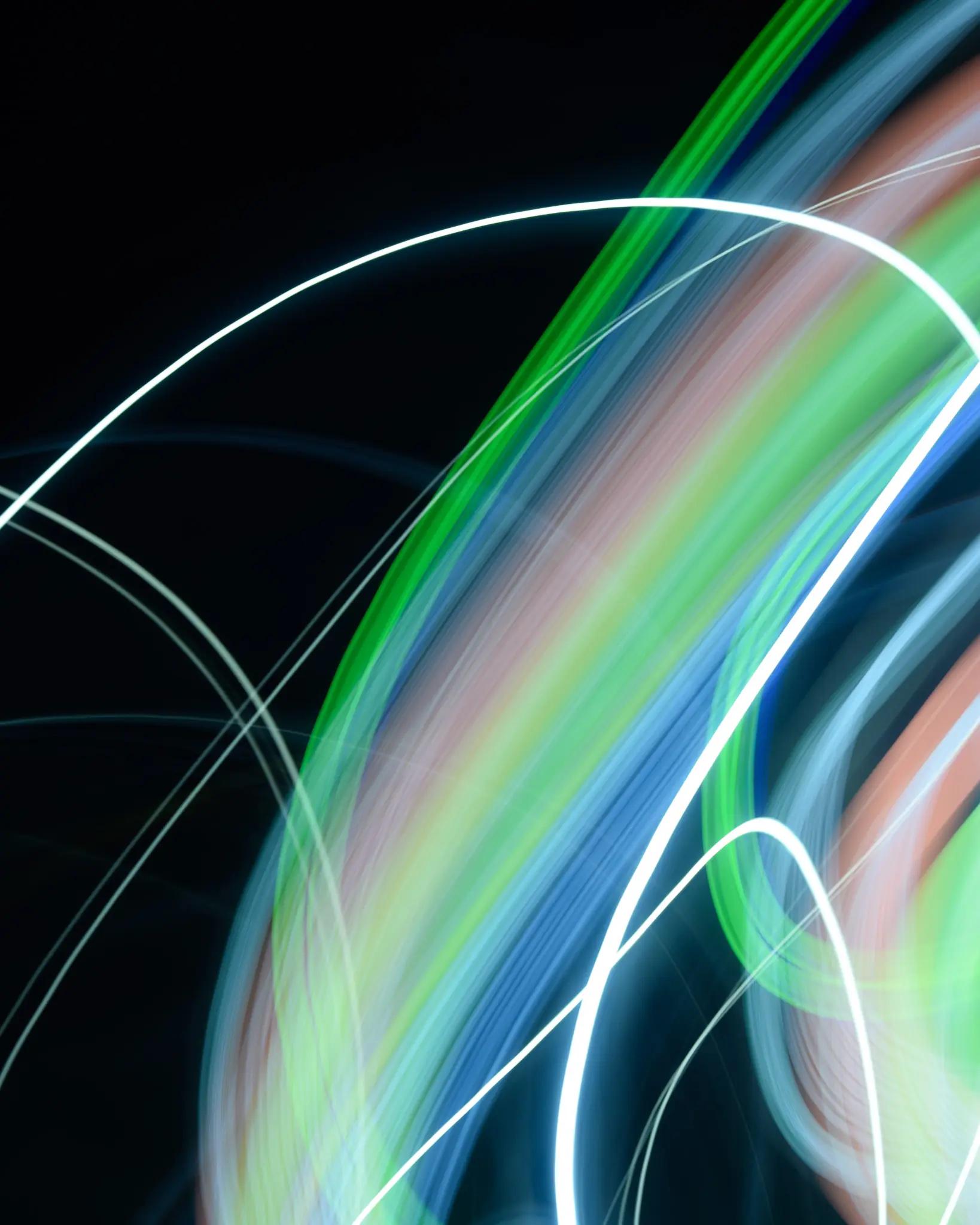 Layered green, cyan, pale red and white light sweeping across black