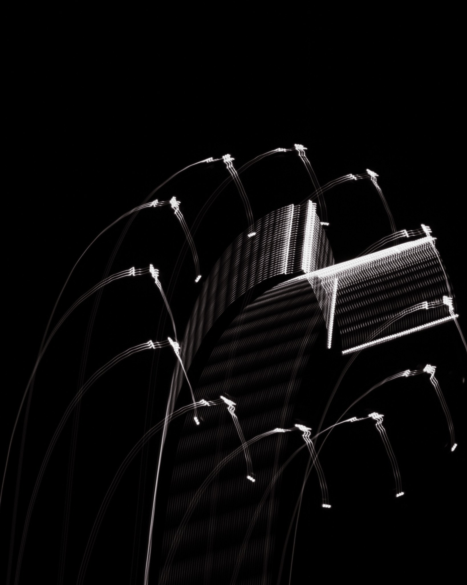 Repeated white lamp traces pull an industrial structure apart against black