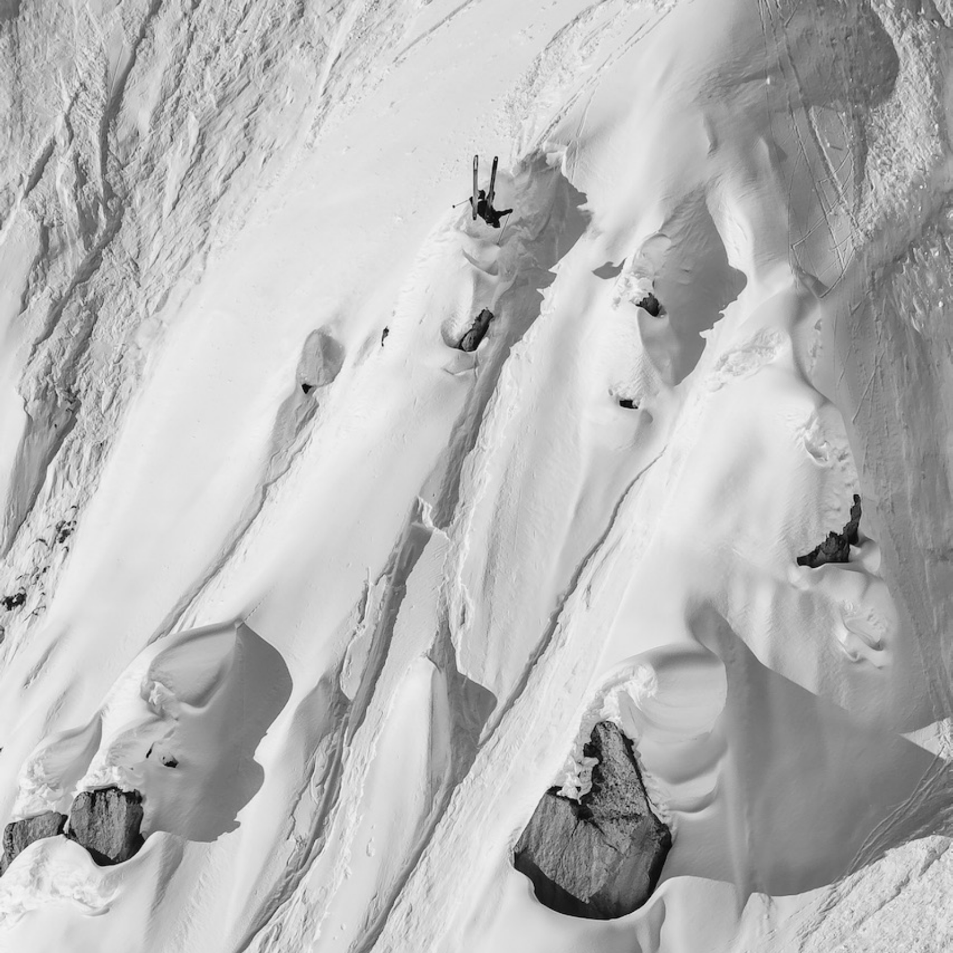 Skier doing a backflip in steep backcountry terrain.
