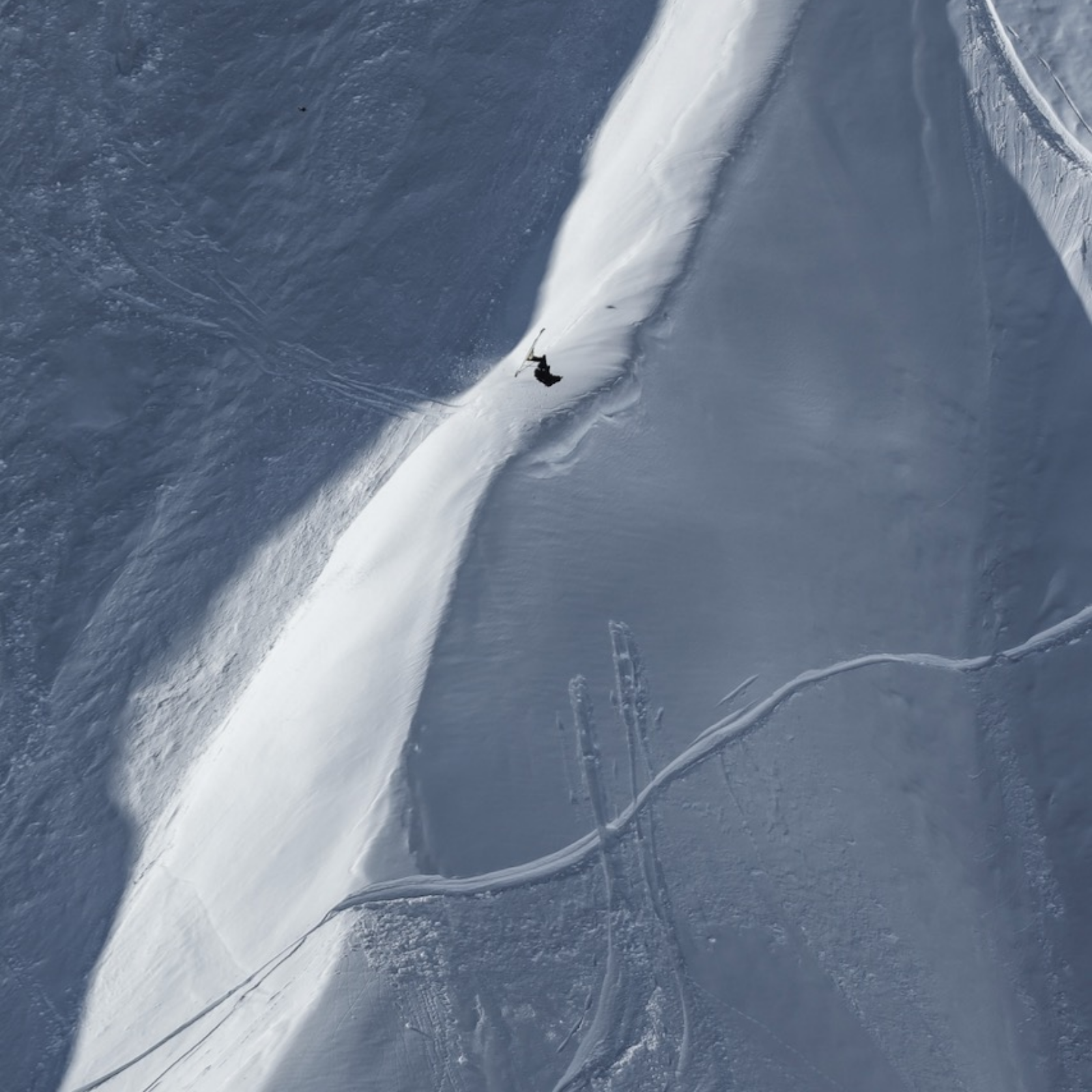 Skier doing a backflip over an edge in off-piste terrain