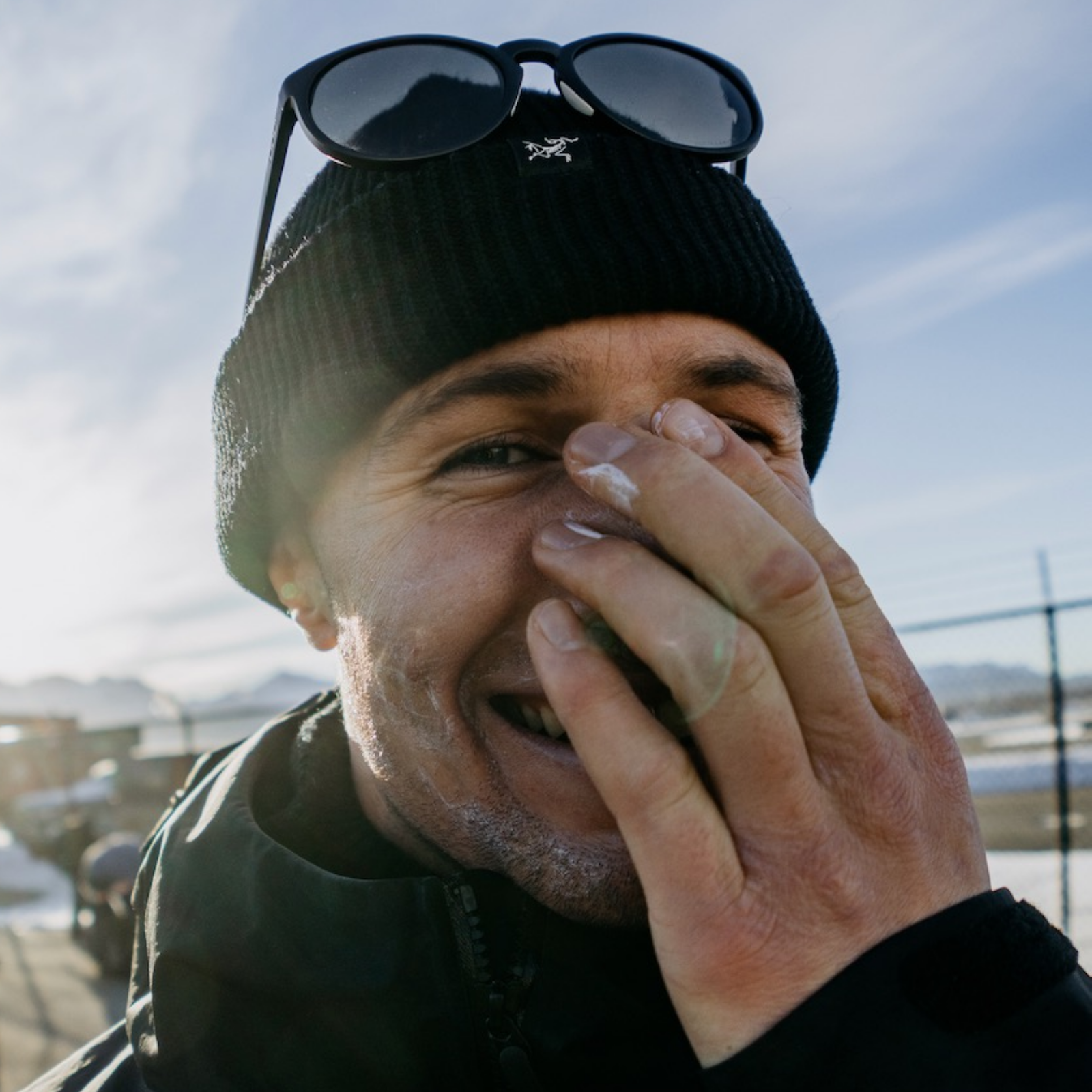 Craig Murray laughing in the sun, covering his face with his hand. 