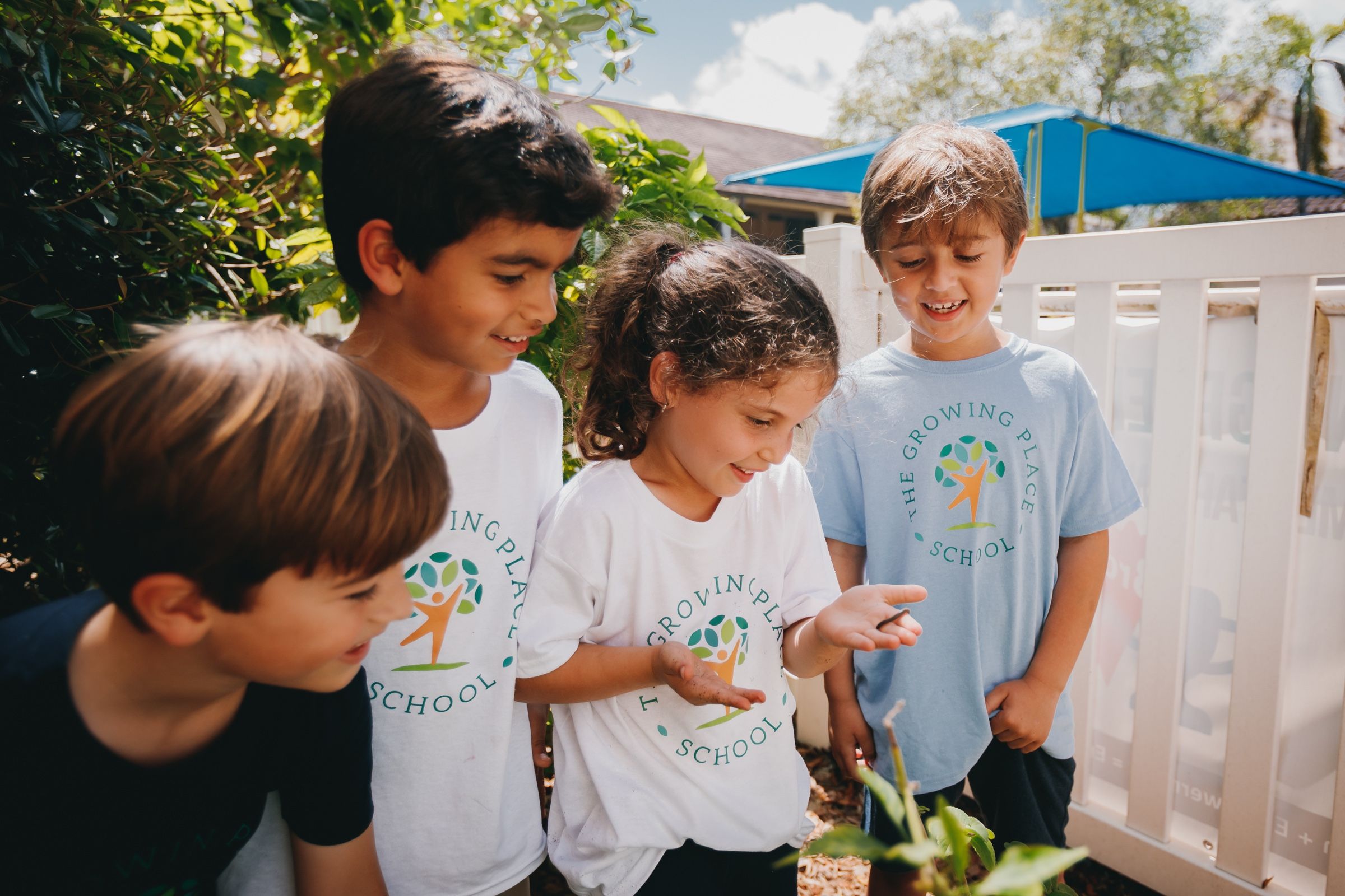Estudiantes observando plantas en el jardín de The Growing Place School