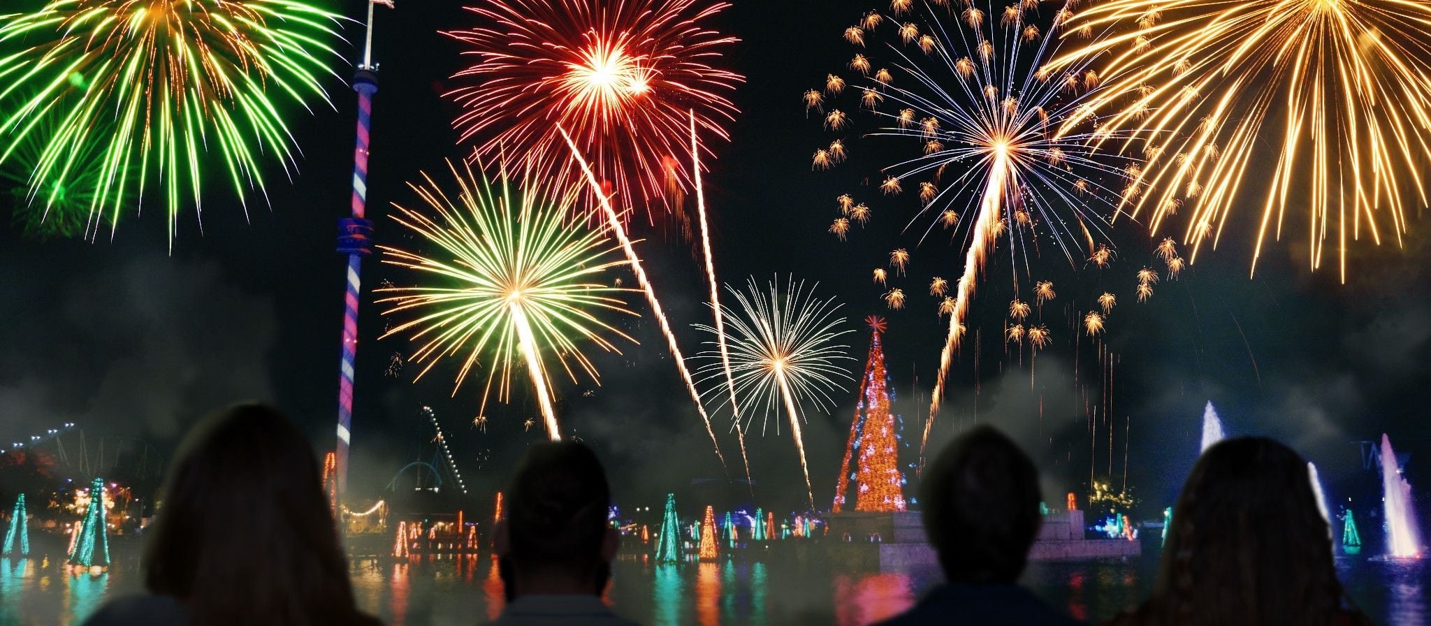 Silhouetted guests watching colorful fireworks over the SeaWorld lagoon