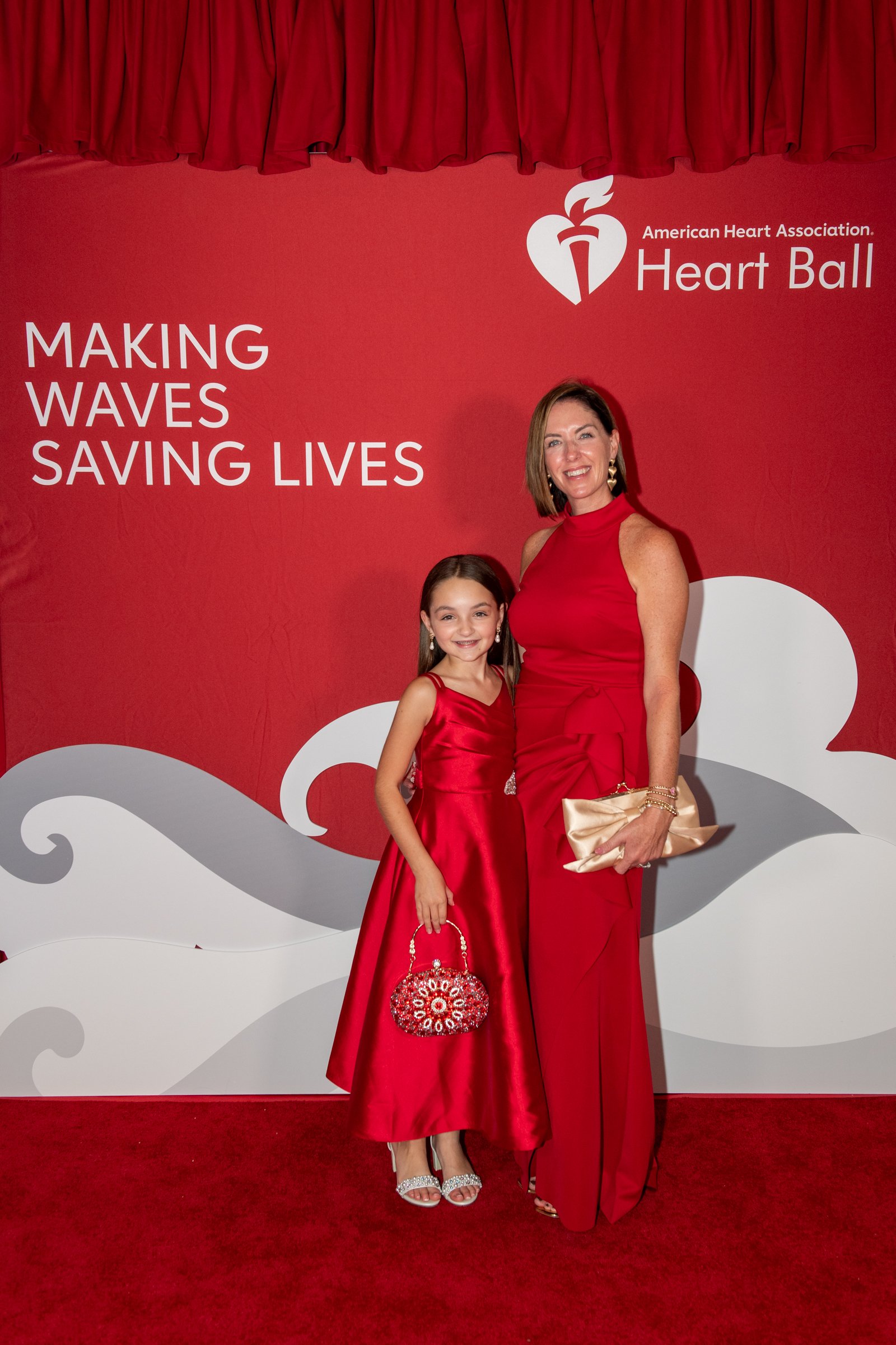 Beth y Evi Mourelatos con vestidos rojos ante el panel del Heart Ball