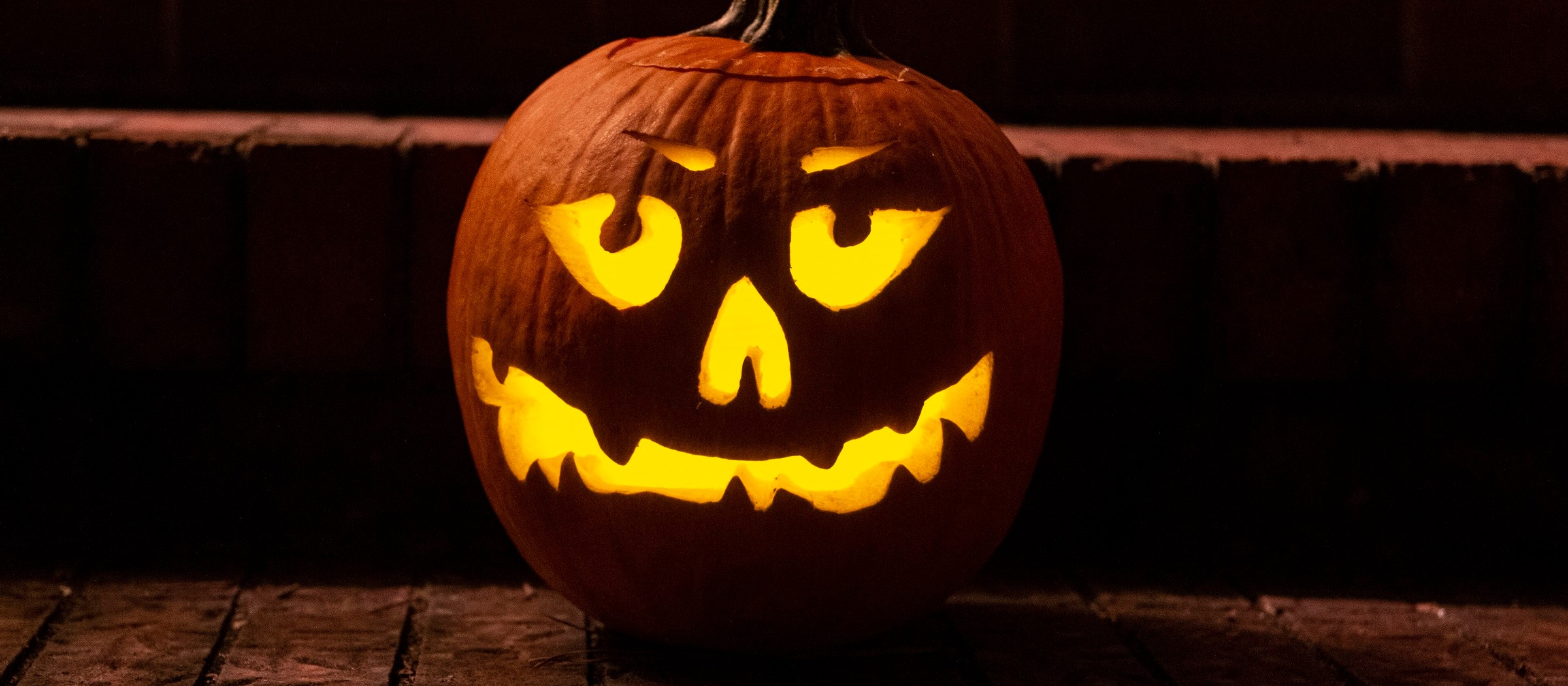 A glowing jack-o'-lantern with a crooked grin on brick steps at night