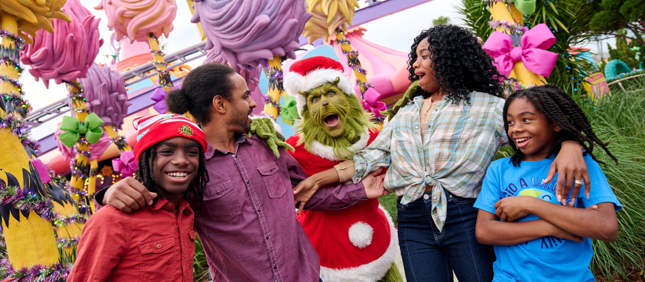 Una familia posando con el Grinch vestido de Santa en Seuss Landing