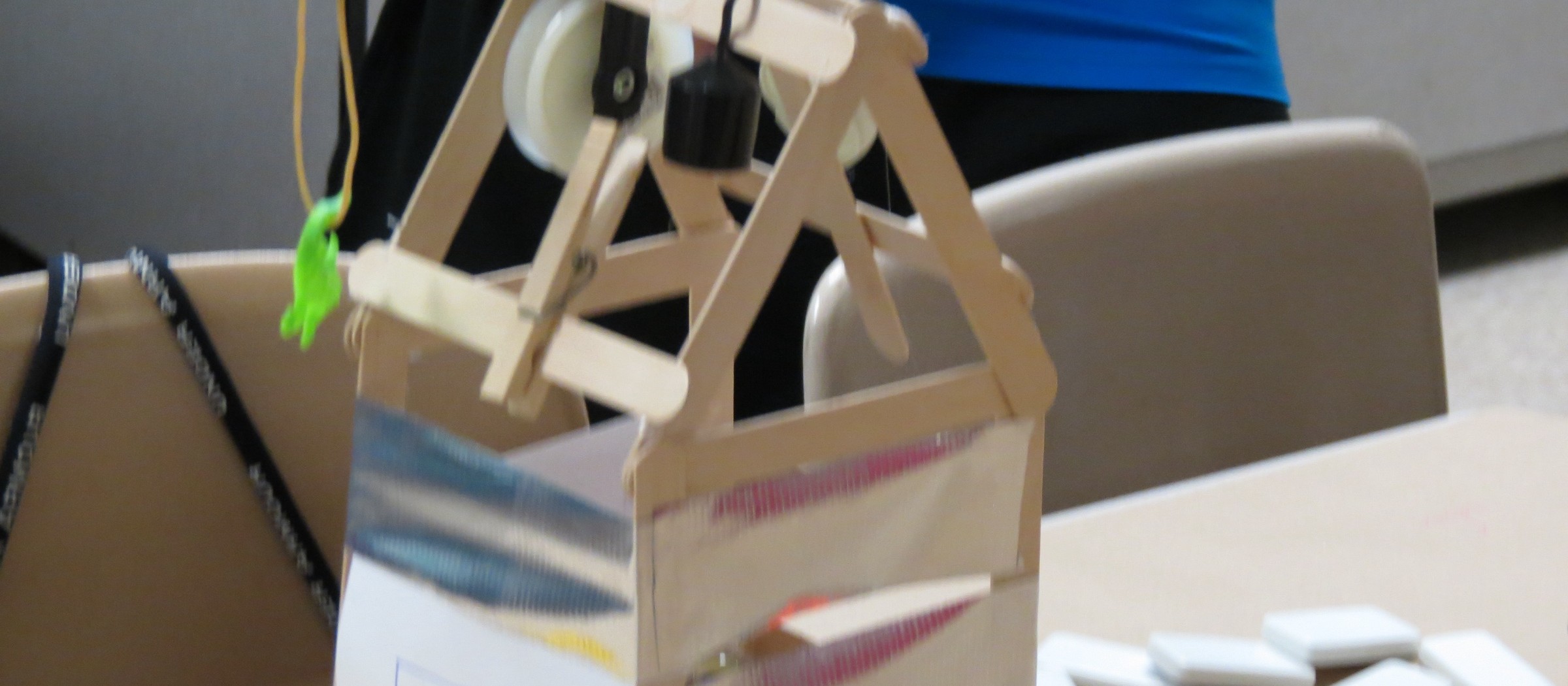 Una máquina de poleas hecha con palitos de madera y una caja de cartón en un campamento STEM para niños