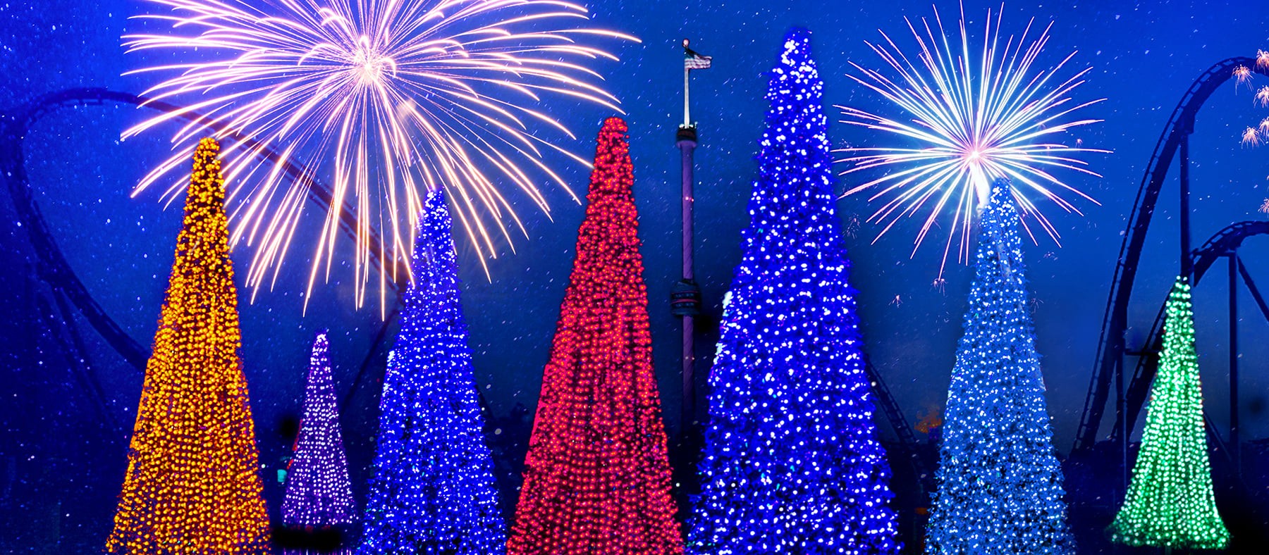 Glowing Christmas trees in rainbow colors with fireworks bursting above them