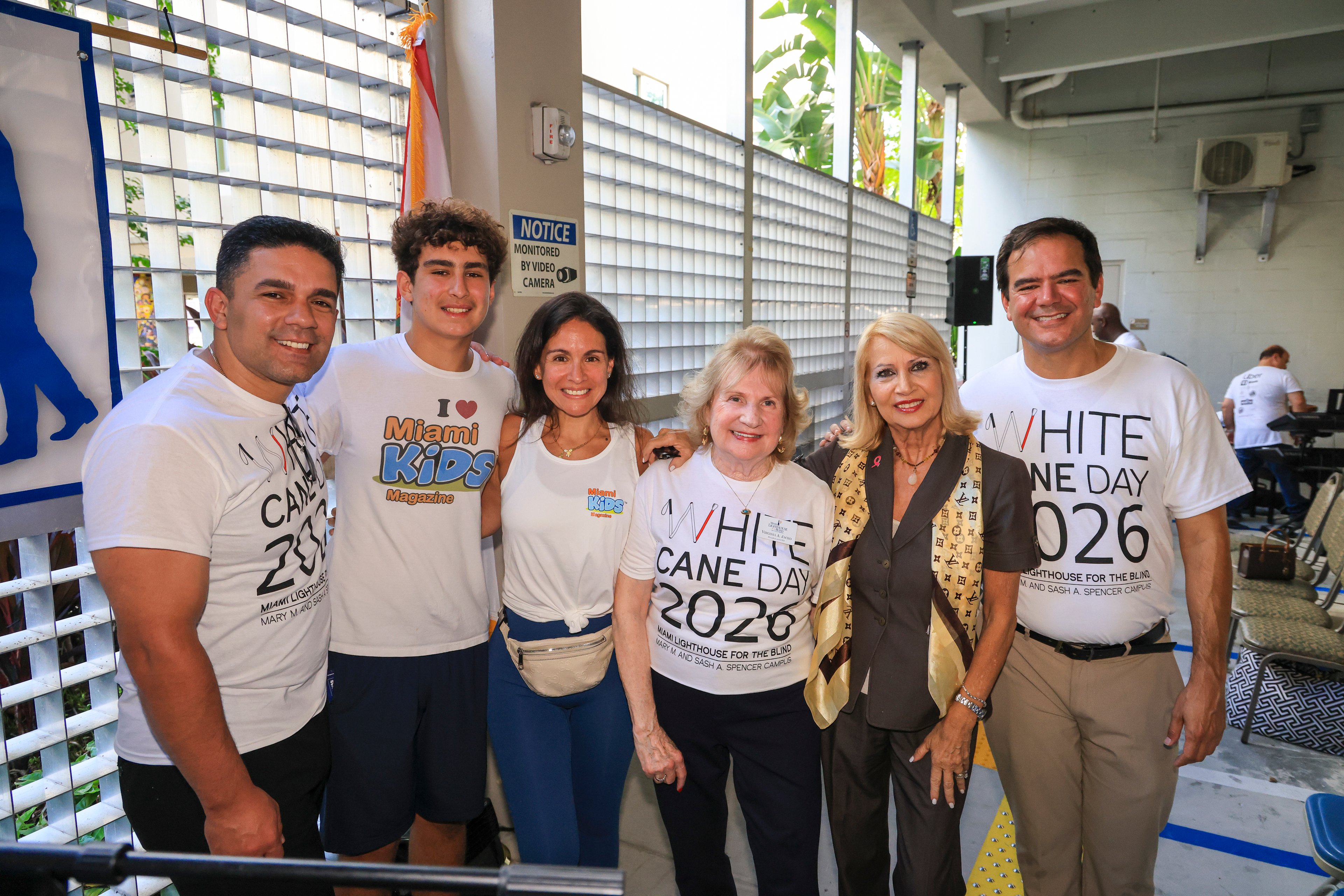 Six guests side by side, three in White Cane Day 2026 T-shirts and two in Miami Kids Magazine shirts