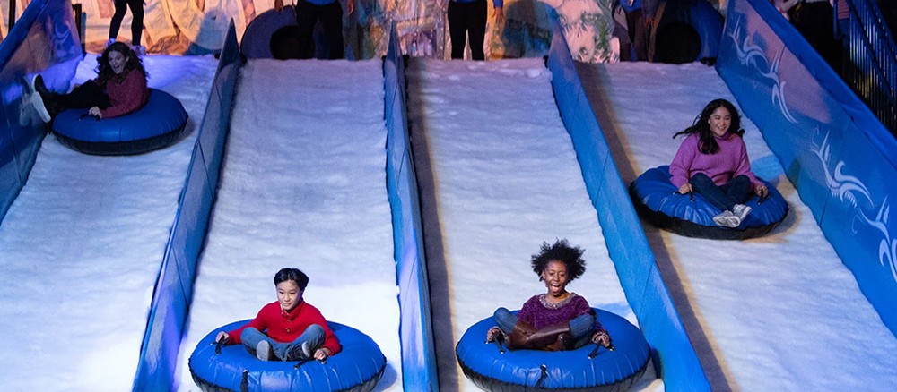 Niños bajando en tubos azules por carriles de hielo paralelos