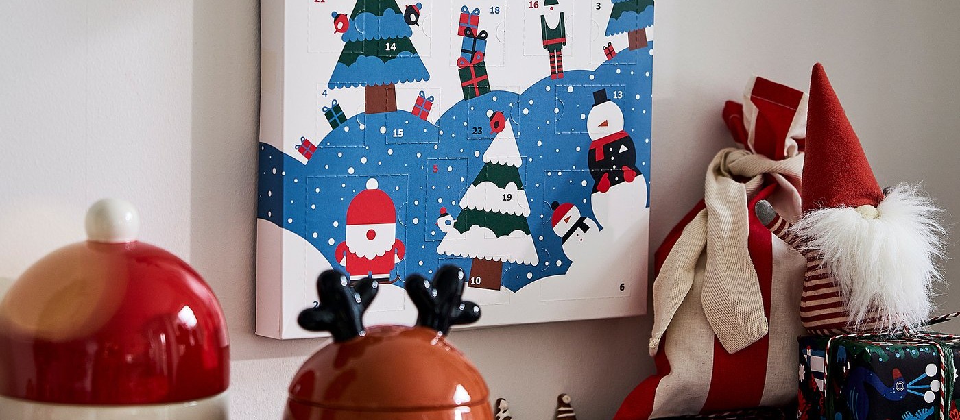 A holiday advent calendar, a reindeer jar, a Santa gnome and wrapped gifts on a shelf