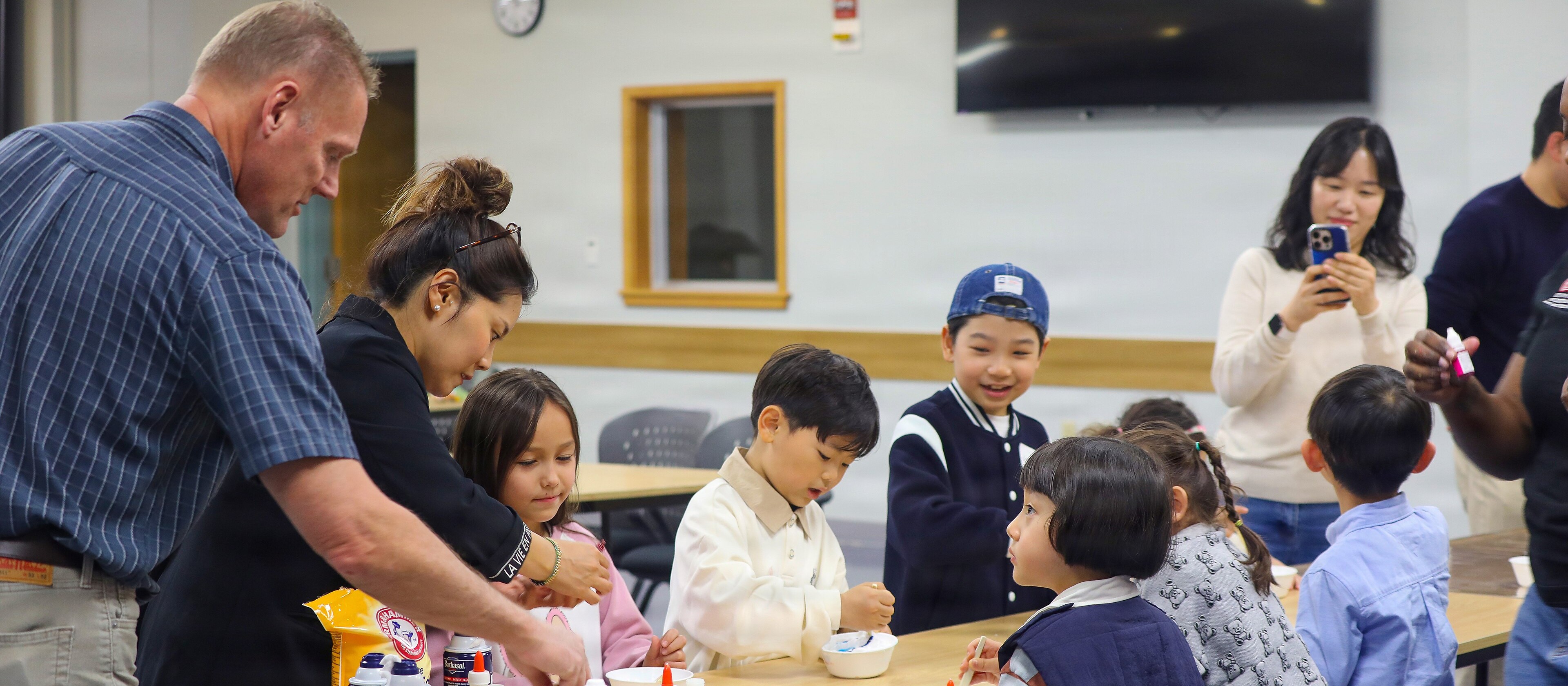 Children making slime with glue at a table, with their parents