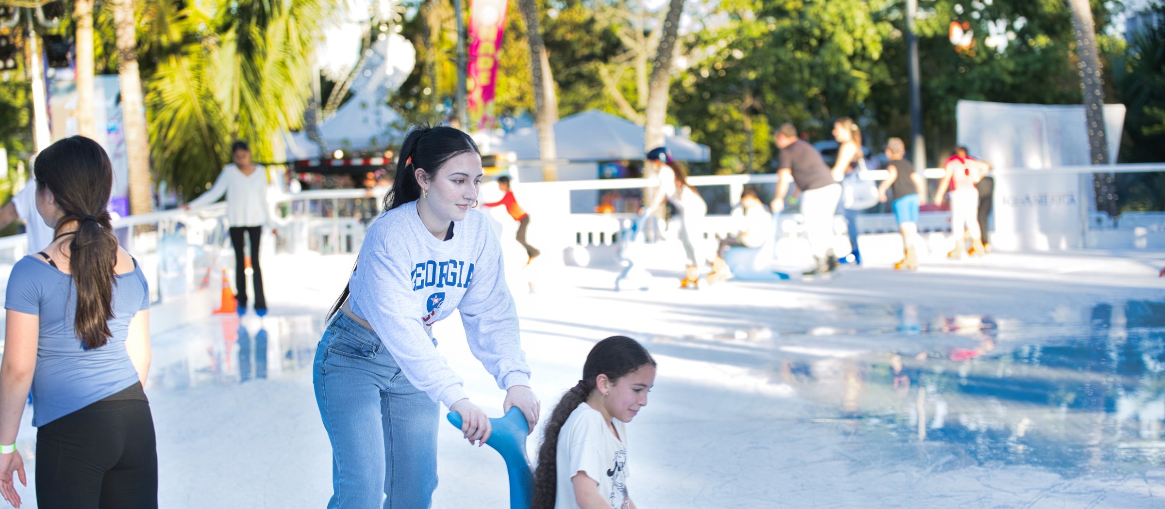 A teenage girl pushes a younger girl on a seal-shaped skating aid at the outdoor ice rink in Losner Park