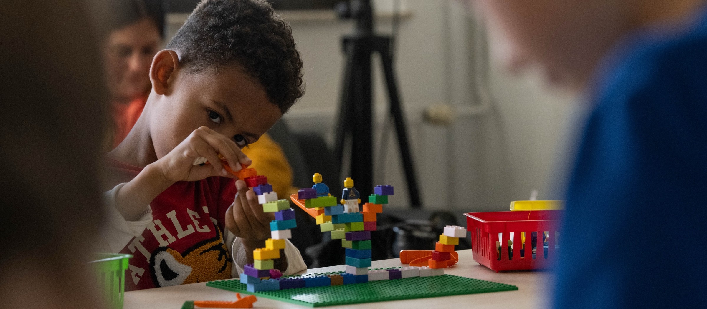 Un niño construye con bloques LEGO en la mesa del club de LEGO de una biblioteca