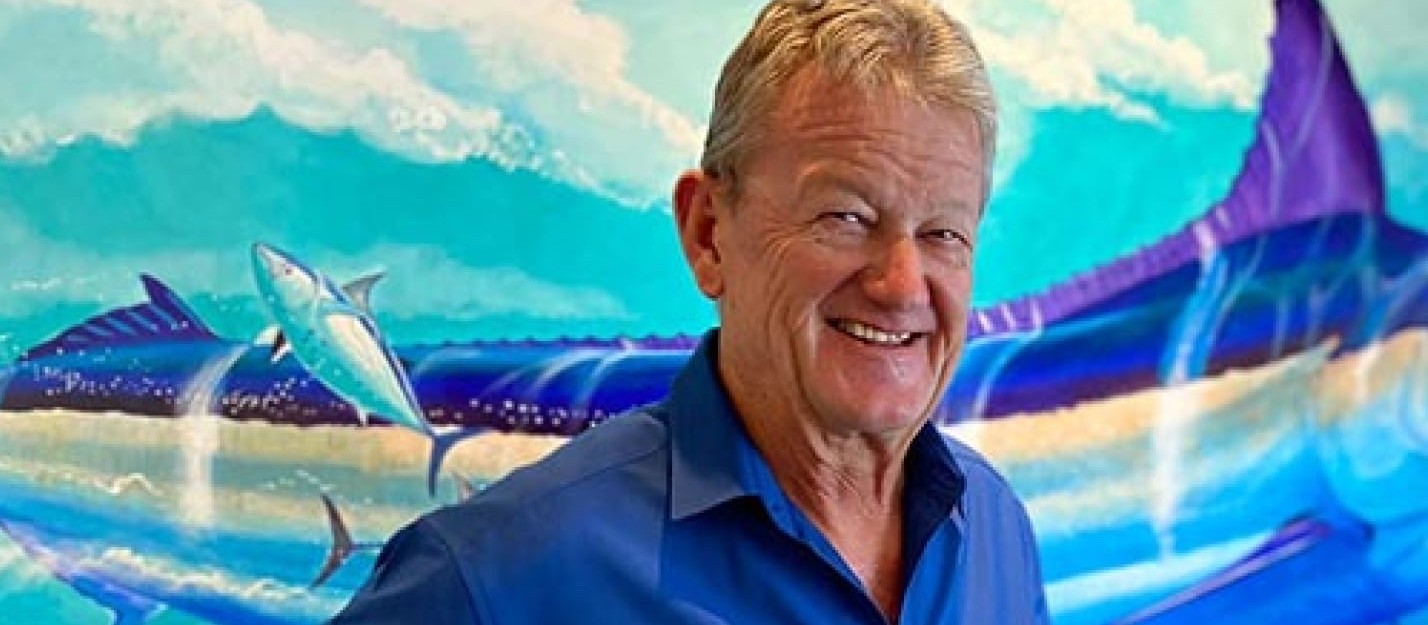 Guy Harvey sonriendo frente a una de sus pinturas de marlines