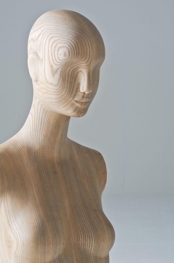 wooden female mannequin against a grey studio background