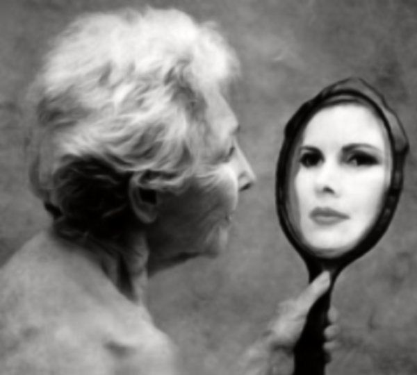 An older woman holding a mirror that reflects a younger face.