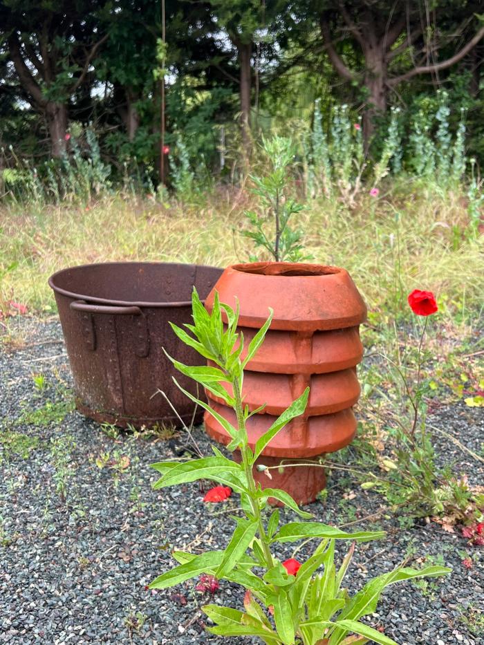 A reclaimed terracotta chimney pot and cast-iron wash boiler used as garden features
