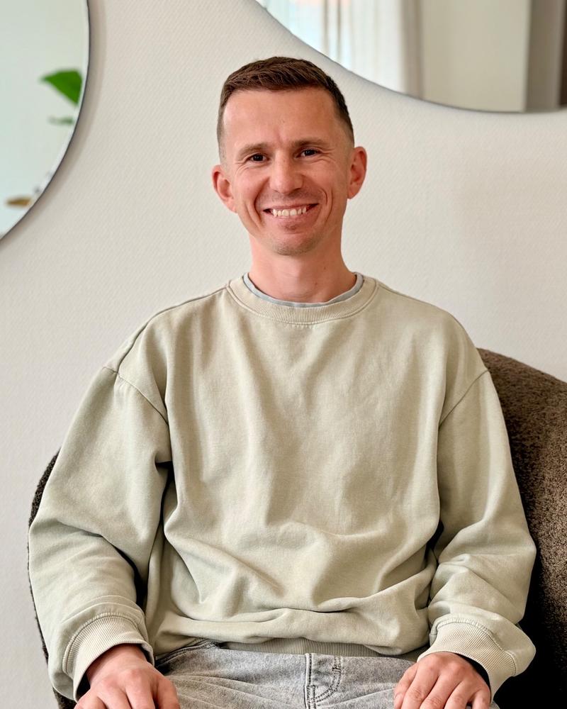Vitaliy i lys sweatshirt smiler i en lænestol