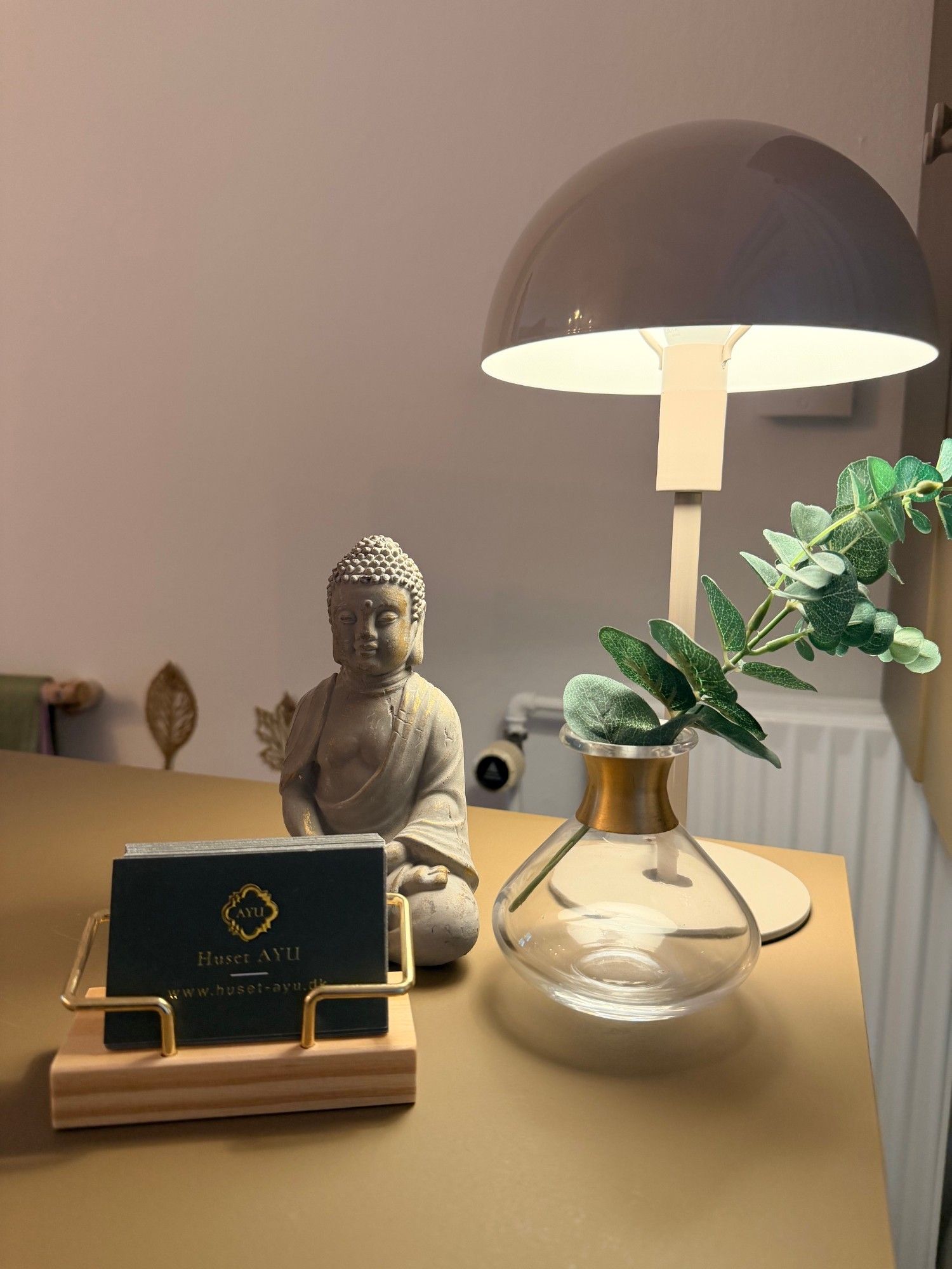 Buddha-figur, bordlampe og visitkort fra Huset Ayu i receptionen