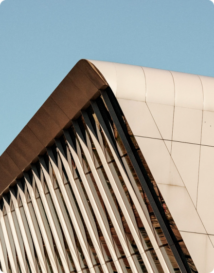 Close-up of a modern architectural building with angled white panels and vertical slats against a clear blue sky.