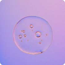 Close-up of a translucent liquid droplet with multiple small bubbles inside, set against a gradient purple and pink background.