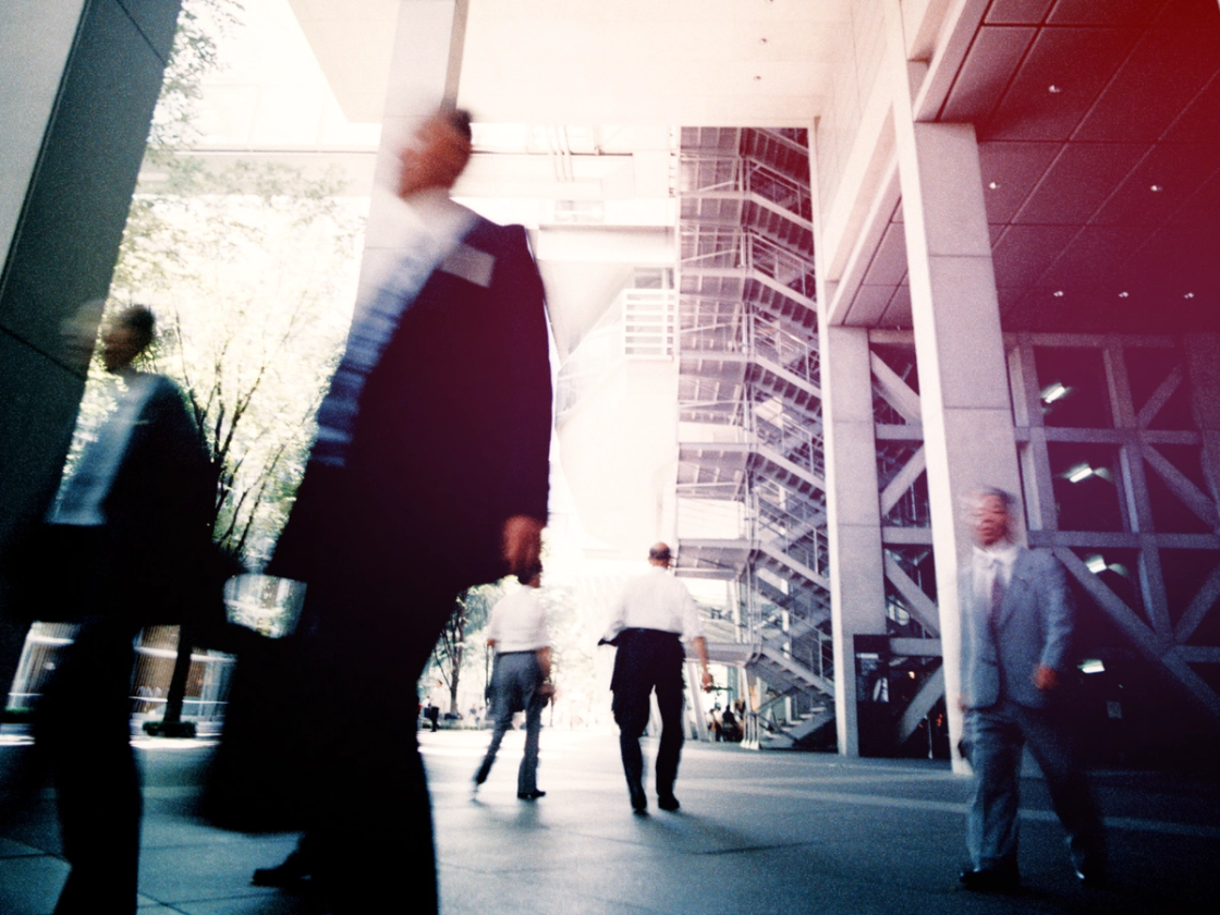 Atomicwork featured image: Business people walking through a large convention center with bright overhead lights 